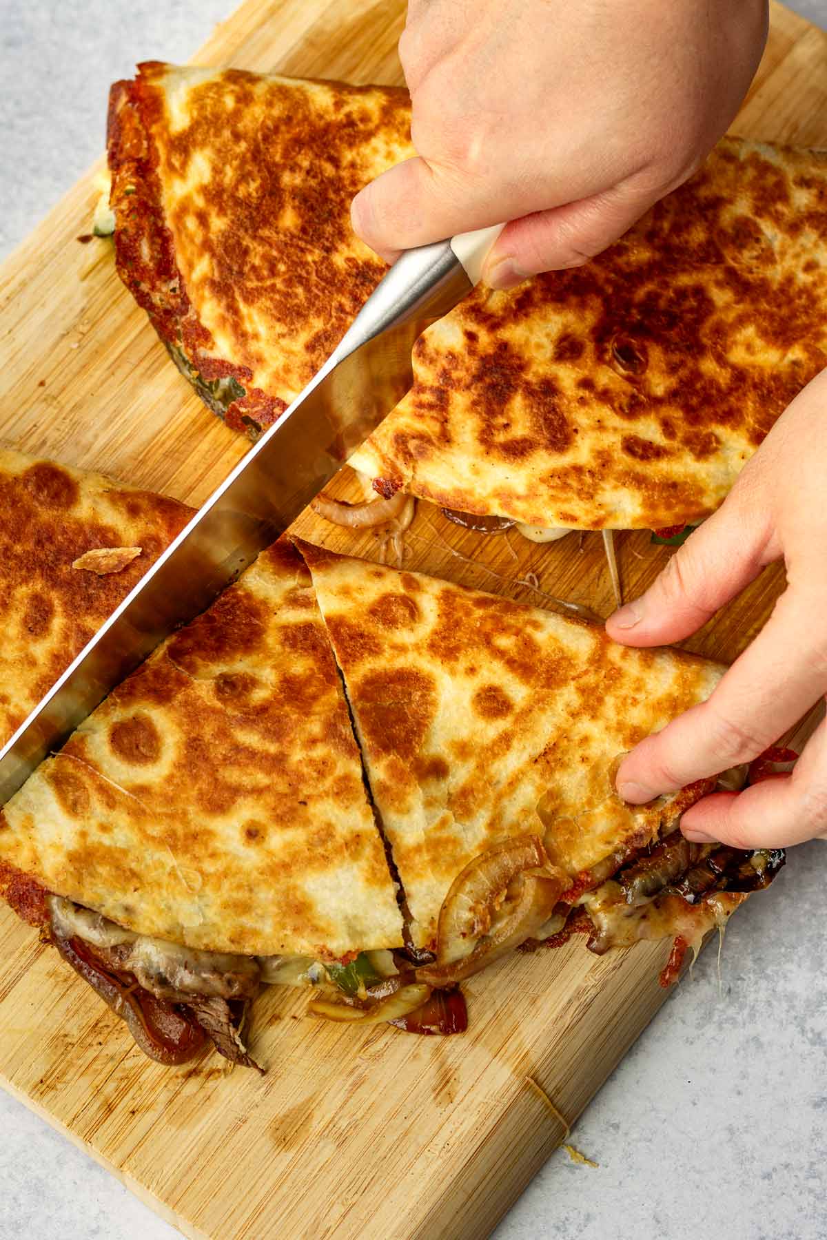 slicing cooked steak quesadillas into three sections