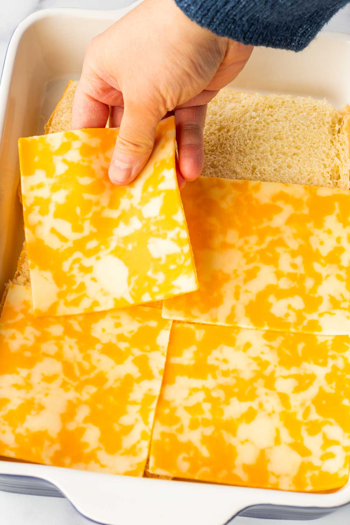 layering cheese on top of sliced slider rolls