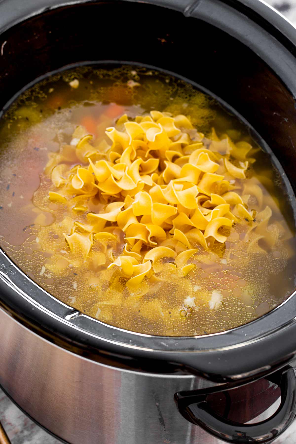 adding egg noodles into the slow cooker