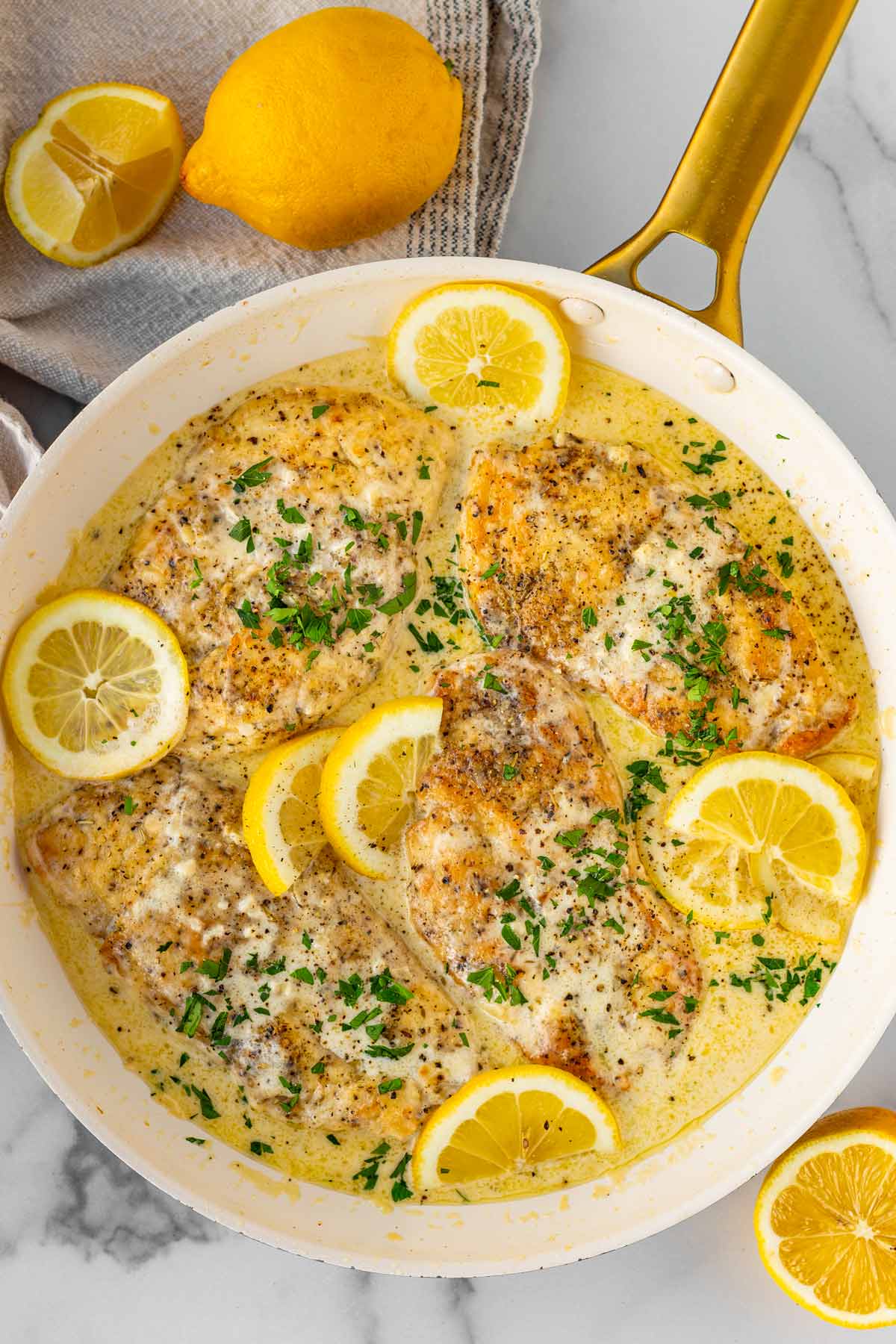 creamy lemon chicken in a skillet with lemon garnish