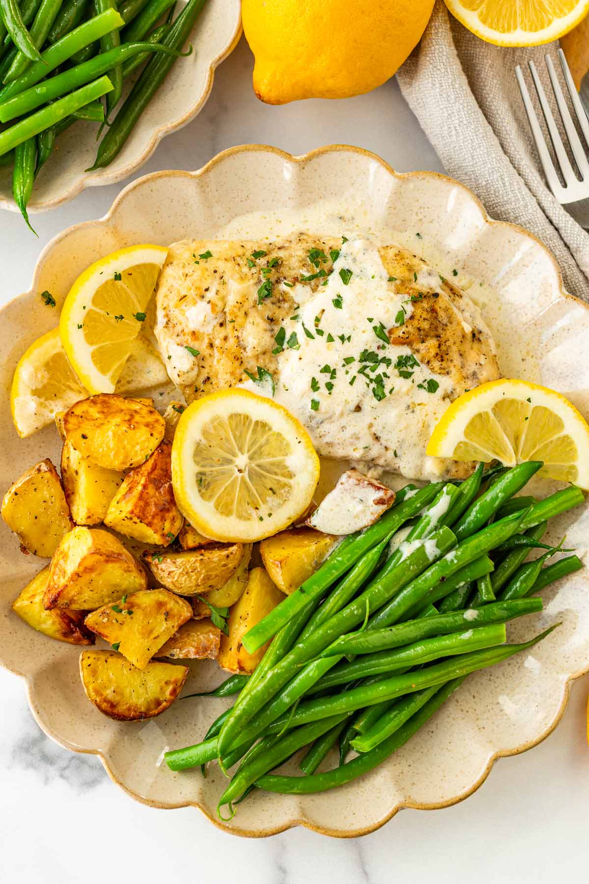 serving of lemon cream chicken on plate with roasted potatoes and green beans