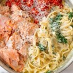 creamy salmon pasta with flaky salmon, roasted jammy tomatoes, and baby spinach with cheese on top