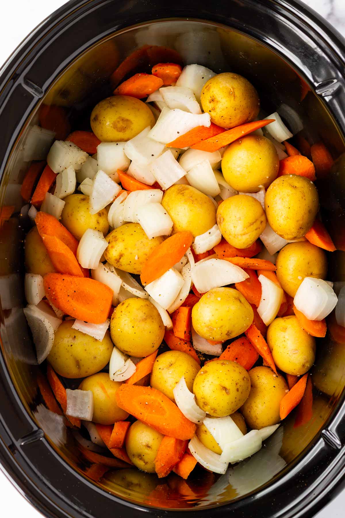 potatoes, carrots, and onions arranged inside a crockpot