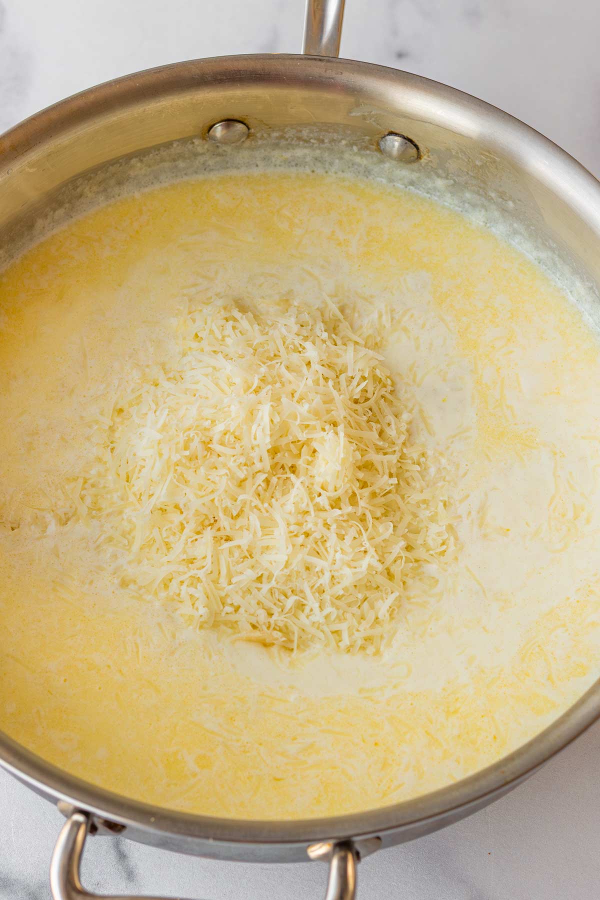forming the cream sauce with heavy cream and freshly grated parmesan cheese in skillet