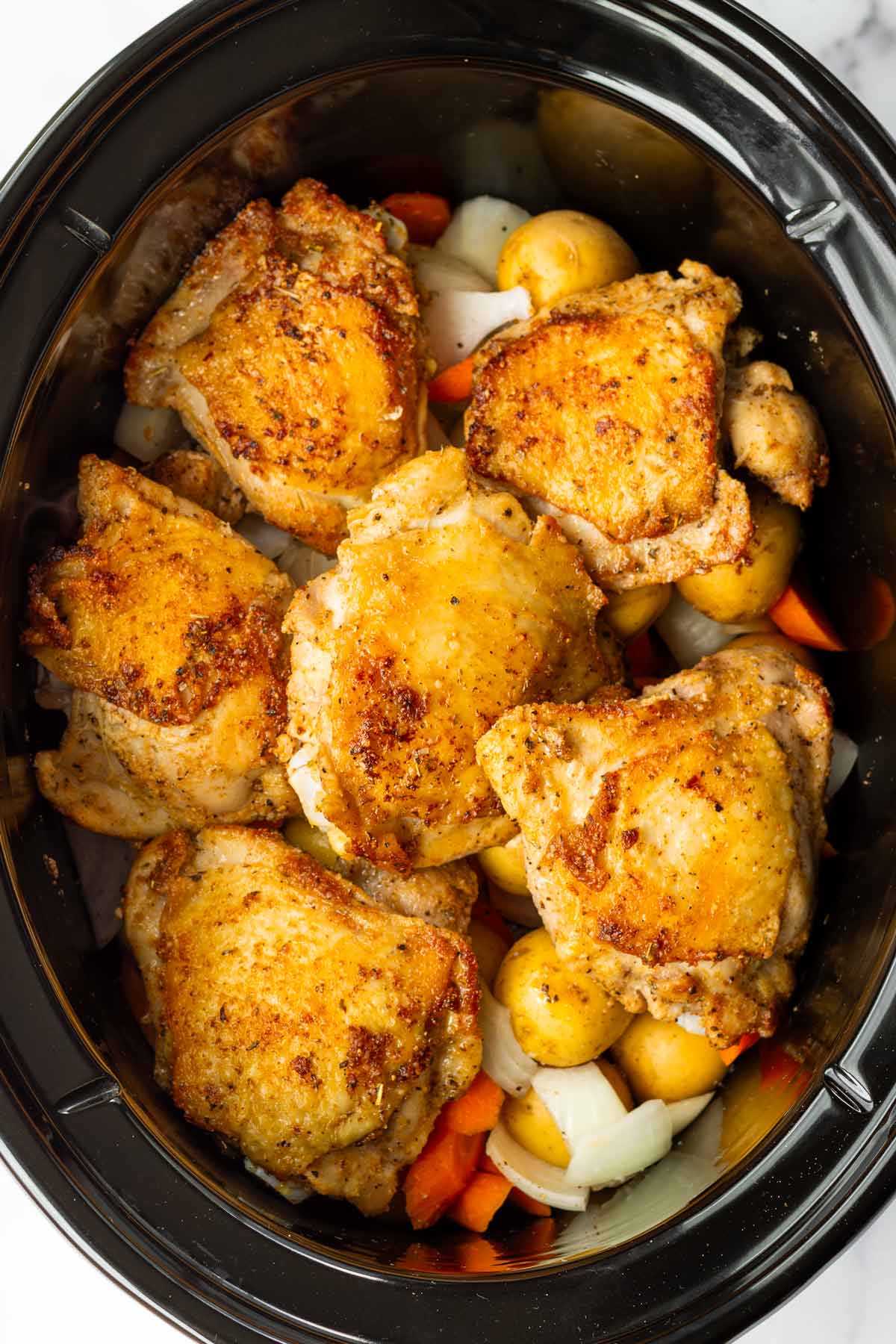 seared chicken on top of the vegetables in a crockpot