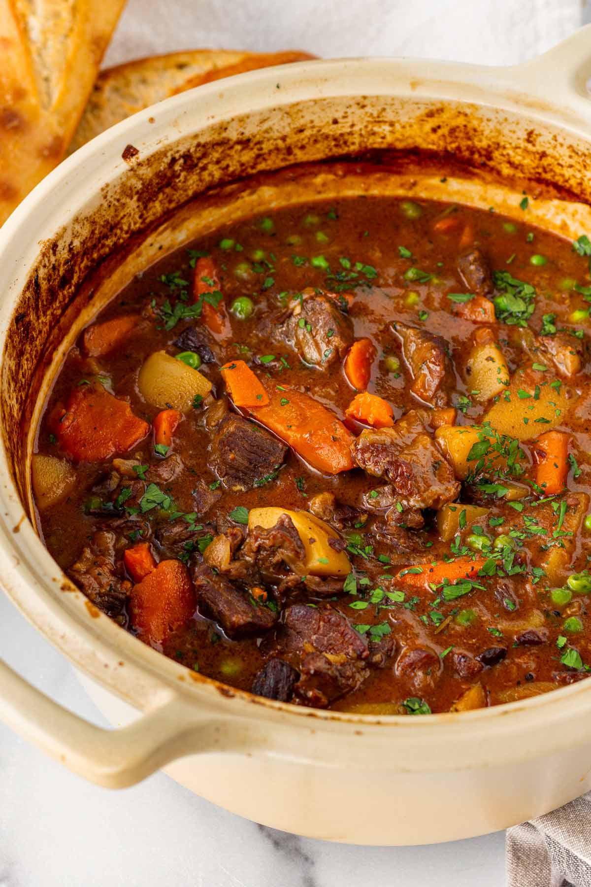 beef stew cooked in a beige dutch oven with a thick and rich gravy