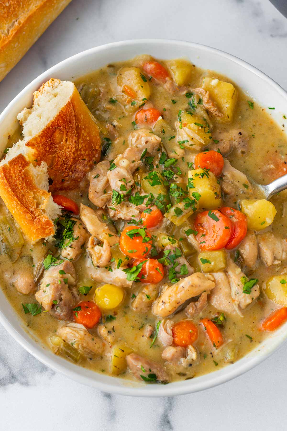 chicken stew in a bowl with baguette