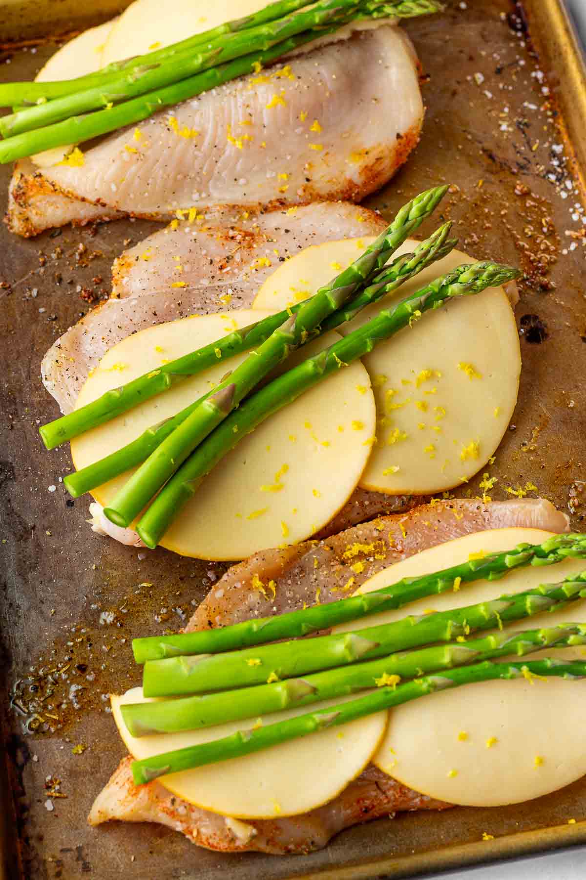 layers of gouda cheese, asparagus, and lemon zest on sliced chicken