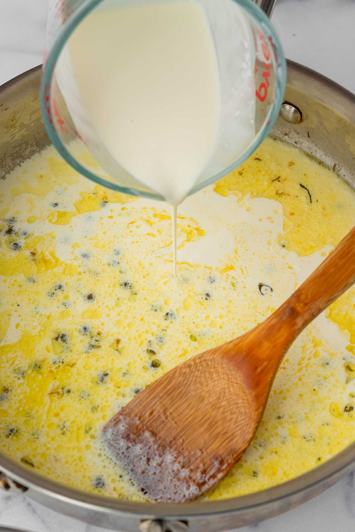 adding cream in the pan to make the sauce