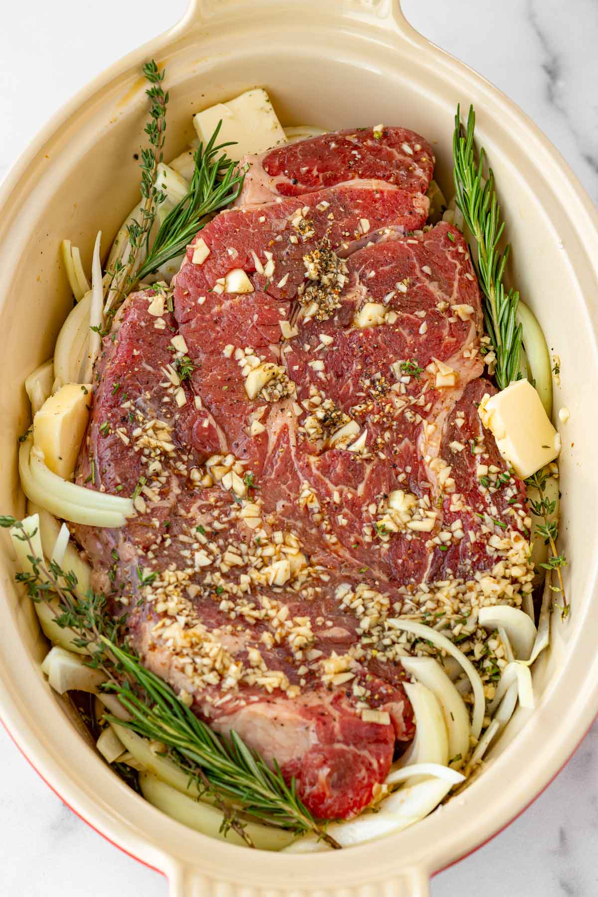 chuck roast assembled with herbs and butter, ready for the oven