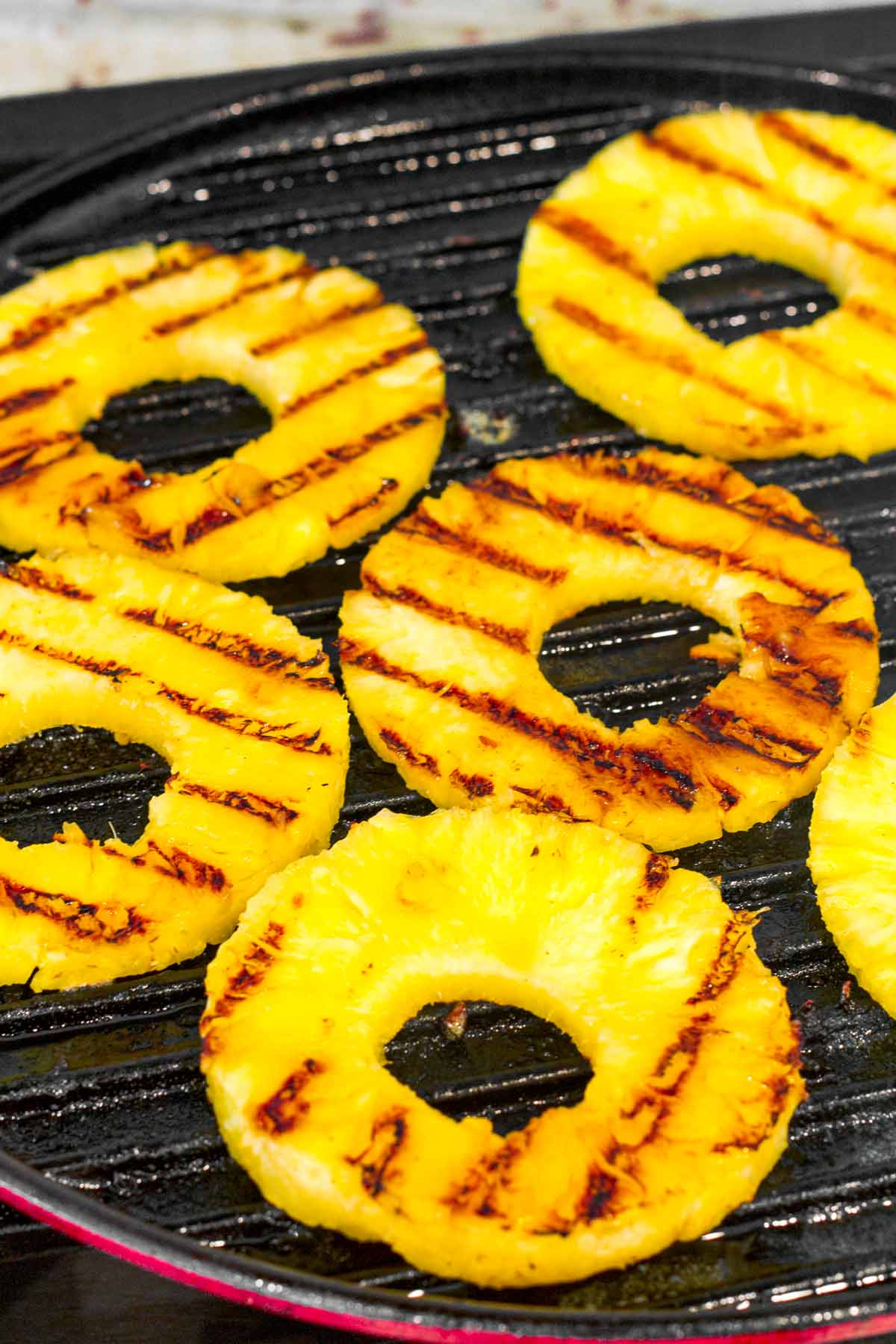 grilling pineapple rings in a round cast iron grill pan