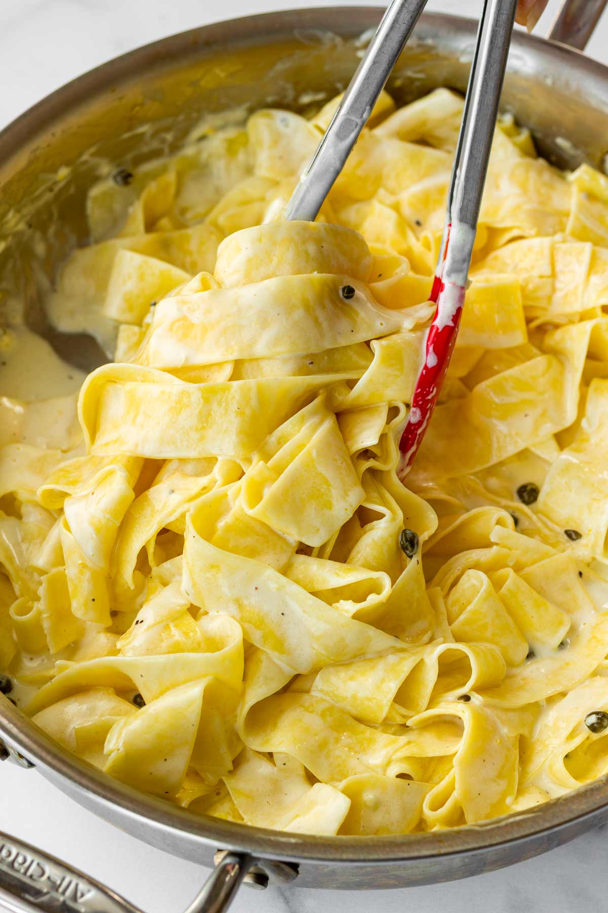 tossing cooked pappardelle noodles with the lemon cream sauce