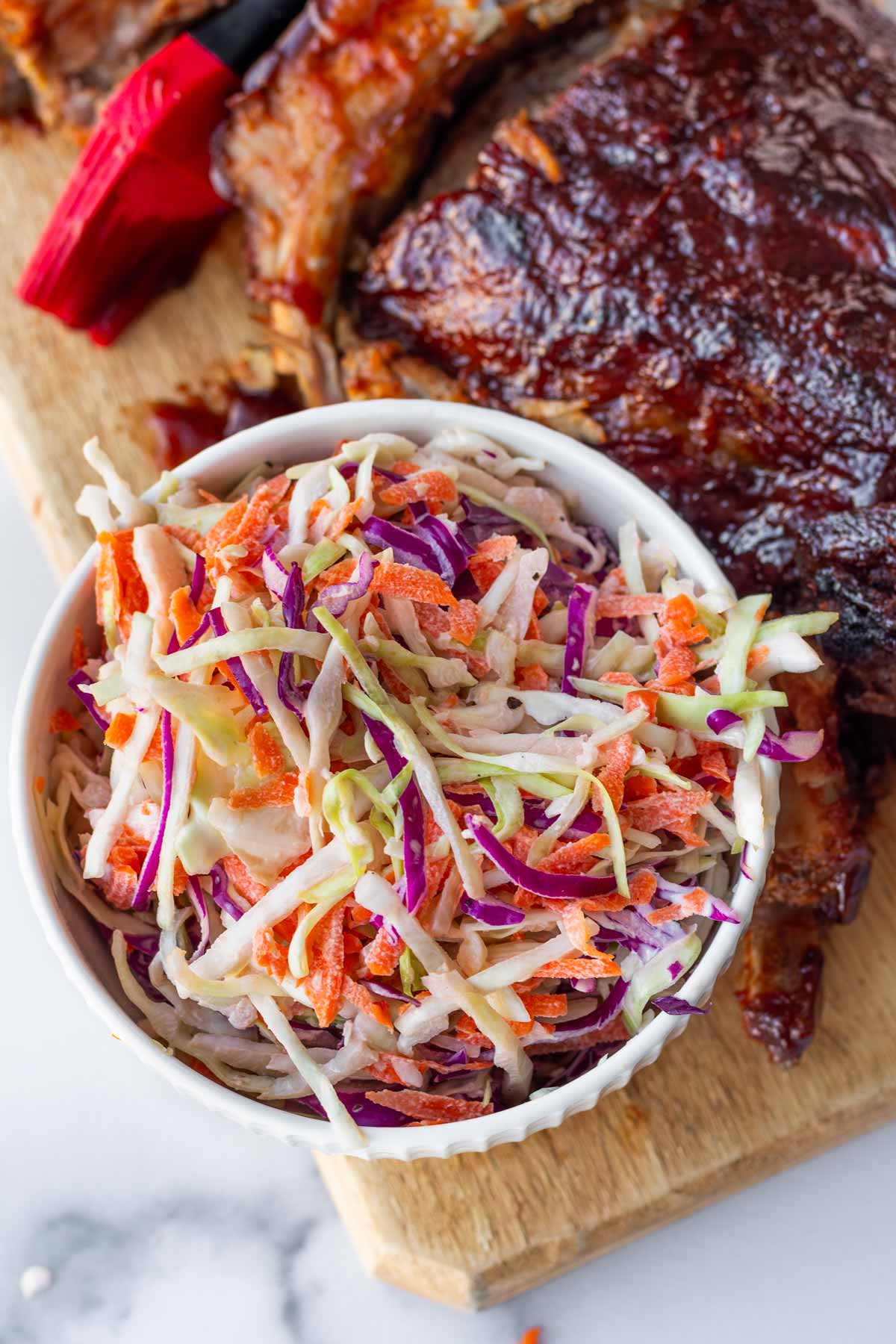 a side bowl of slaw with bbq ribs next to it