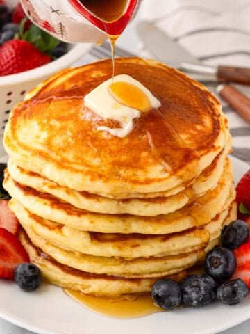 stacked fluffy buttermilk pancakes with berries and maple syrup