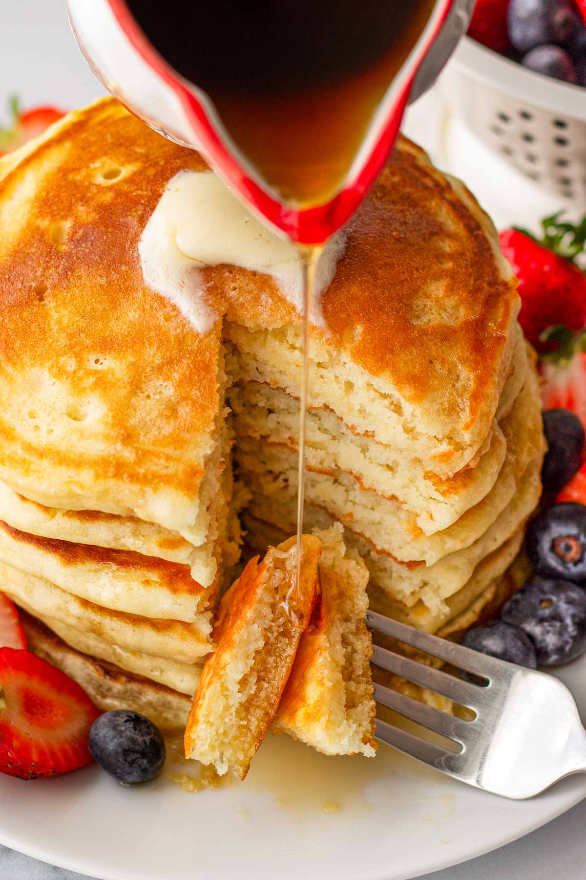 cutting into stack of fluffy pancakes made with buttermilk
