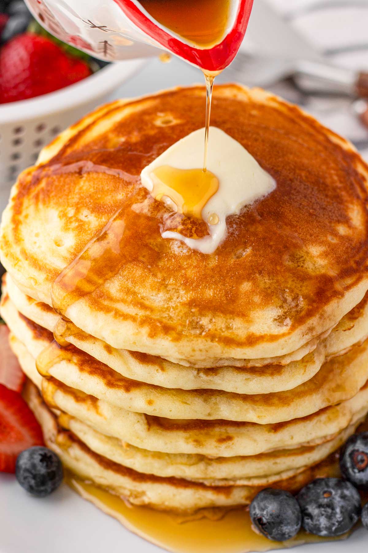 stacked fluffy buttermilk pancakes with butter and maple syrup