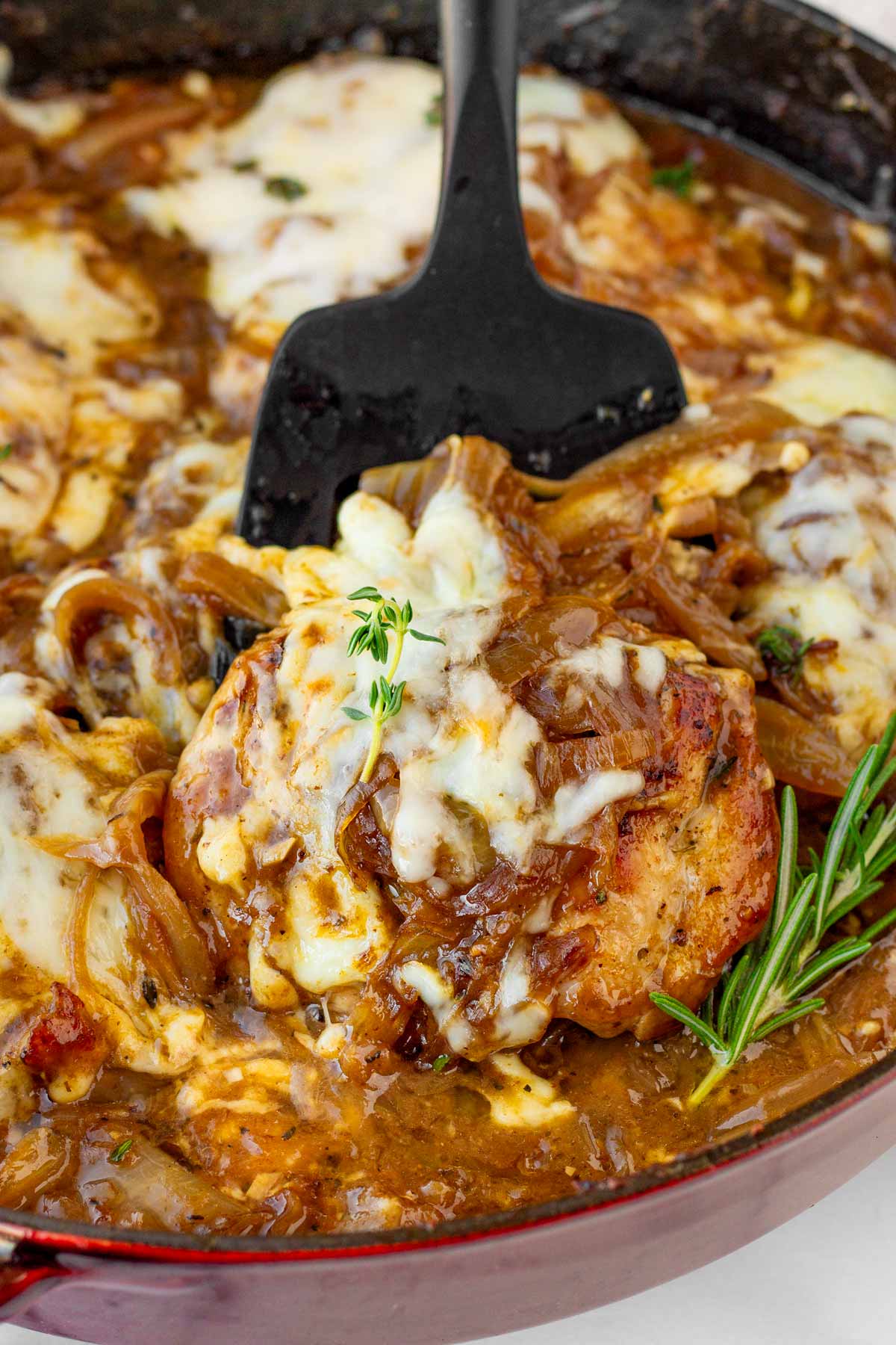 serving a piece of french onion chicken with cheese from the pan