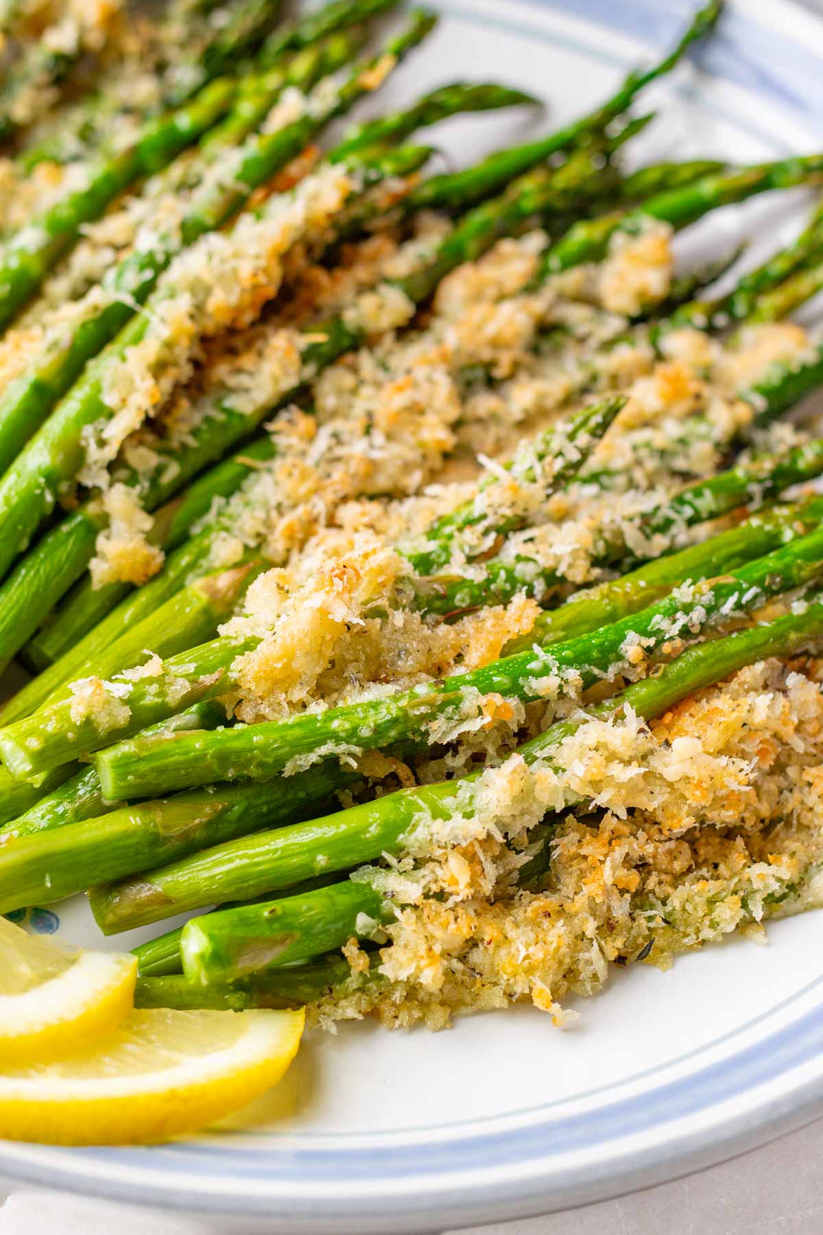 close up of roasted asparagus topped with panko with slices of lemon