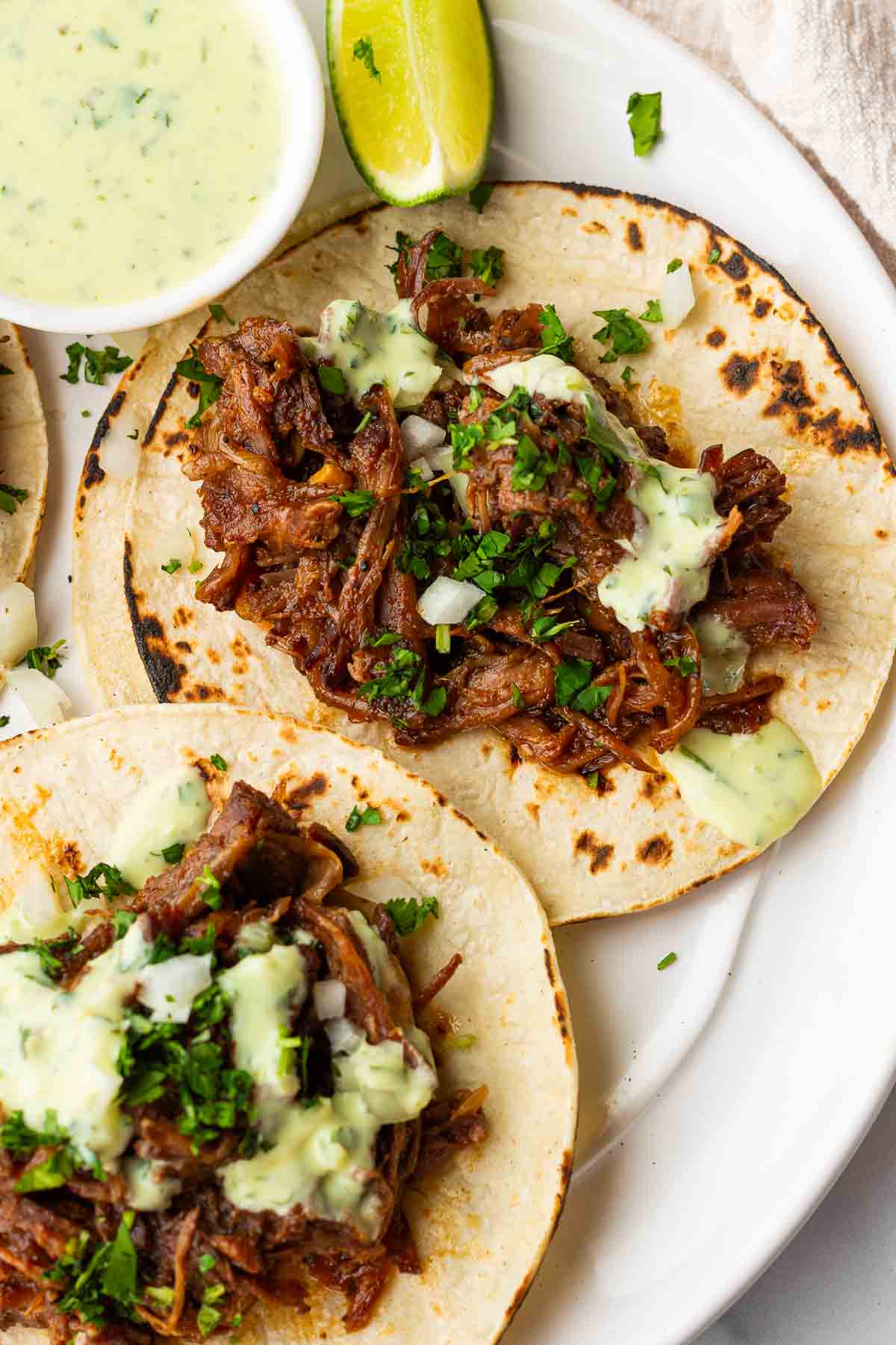two assembled beef tacos with avocado crema