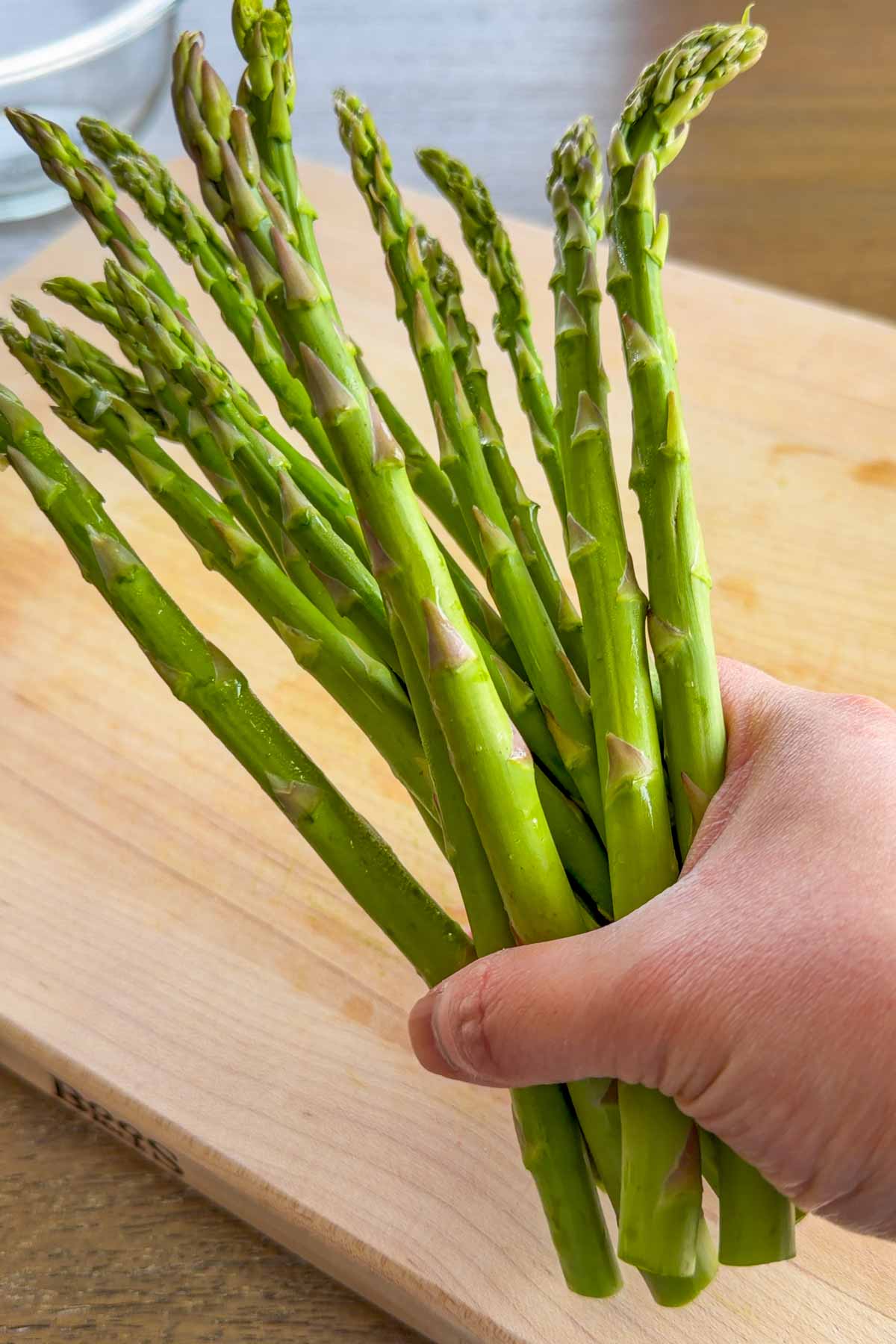 holding a bunch of fresh asparagus on hand