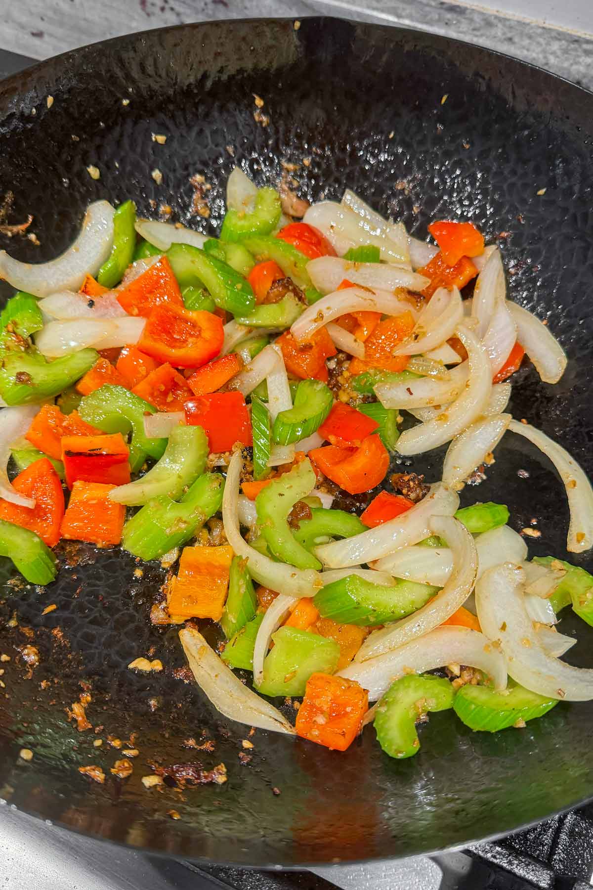 stir frying celery with bell peppers, onions, and aromatics in a wok