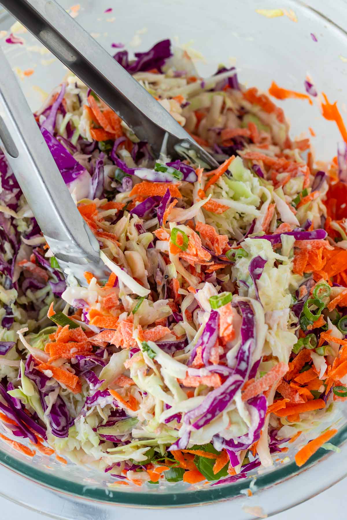 tossing the creamy coleslaw in a bowl