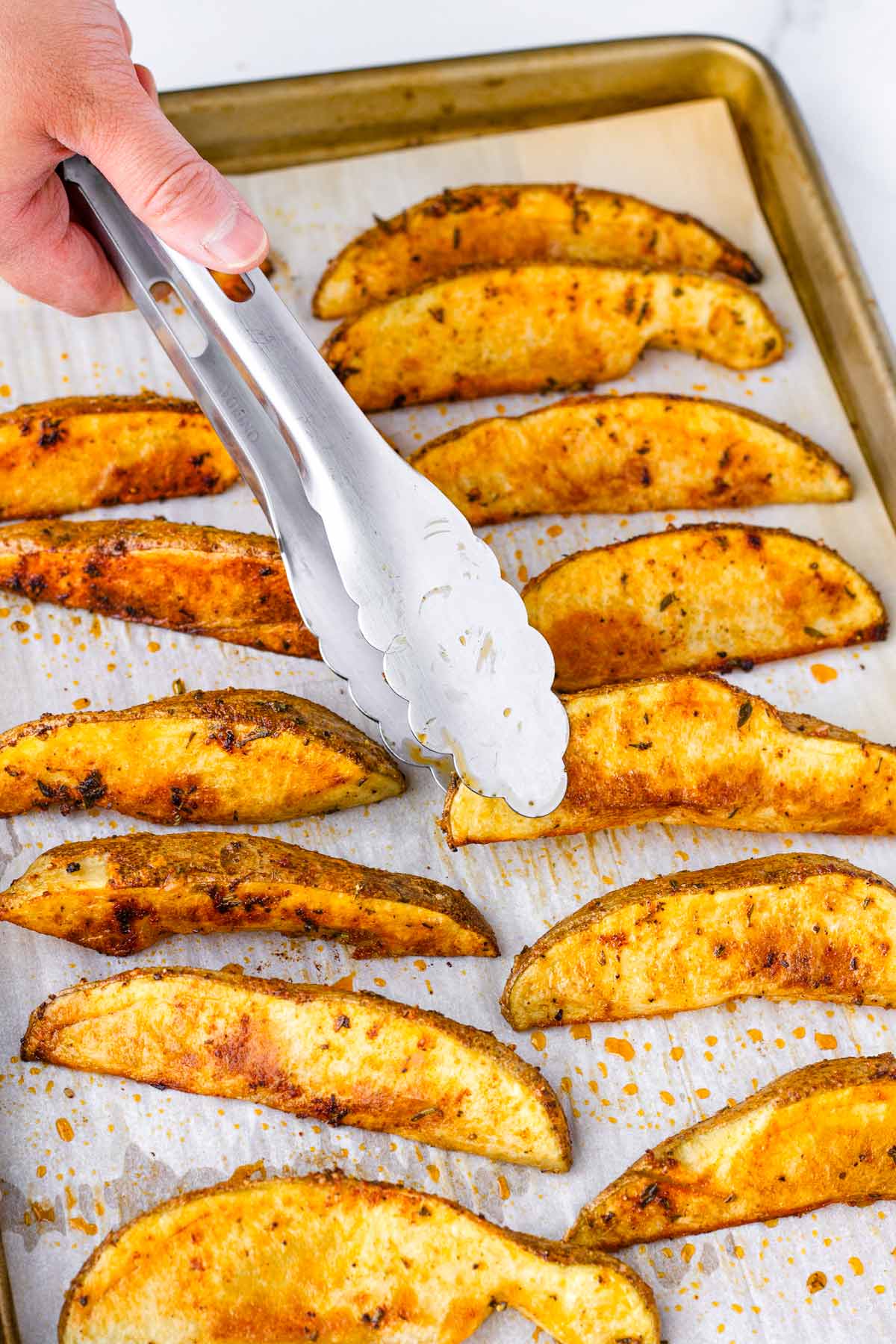 flipping potato wedges with tongs in the sheet pan