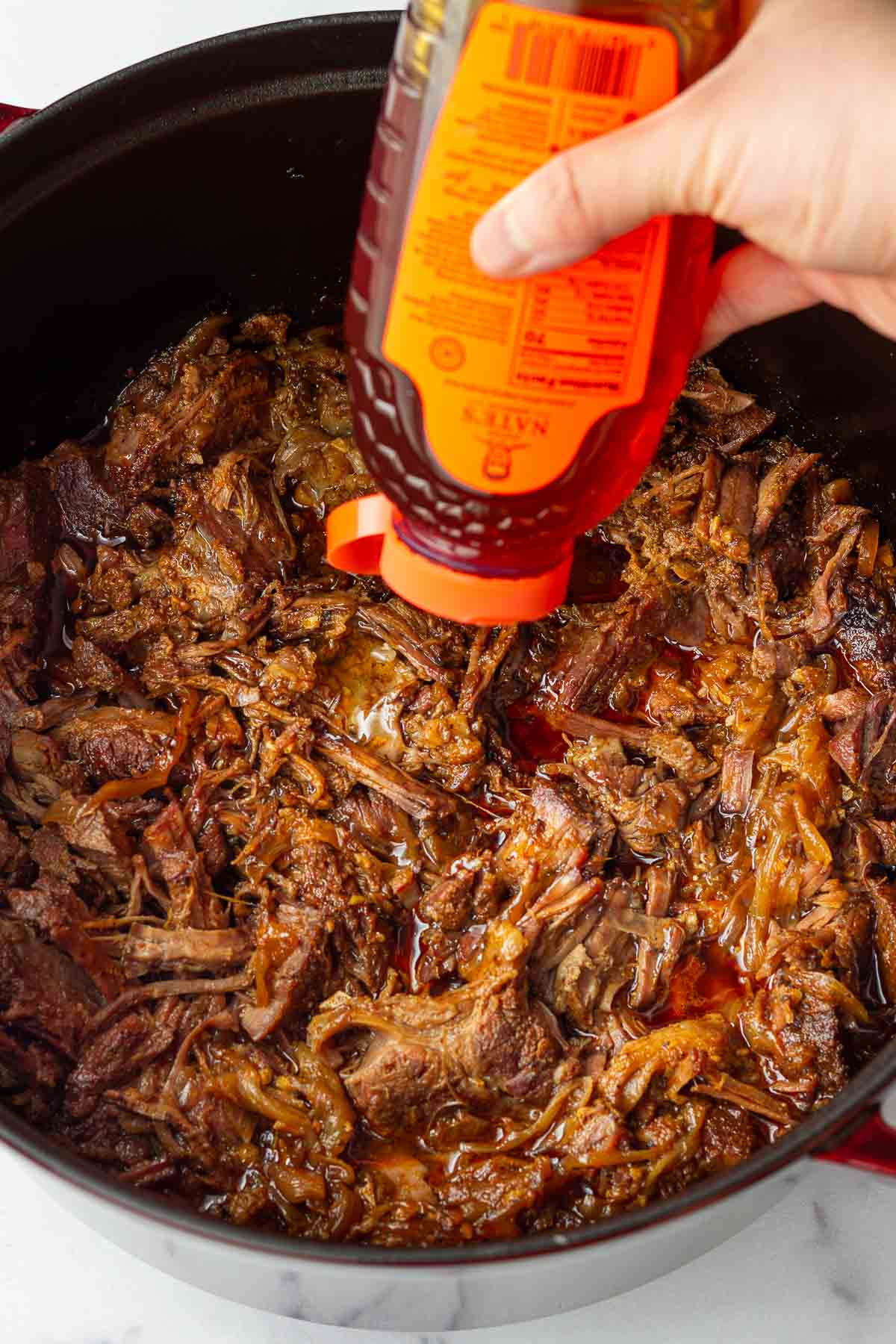 adding honey to the shredded beef in the dutch oven