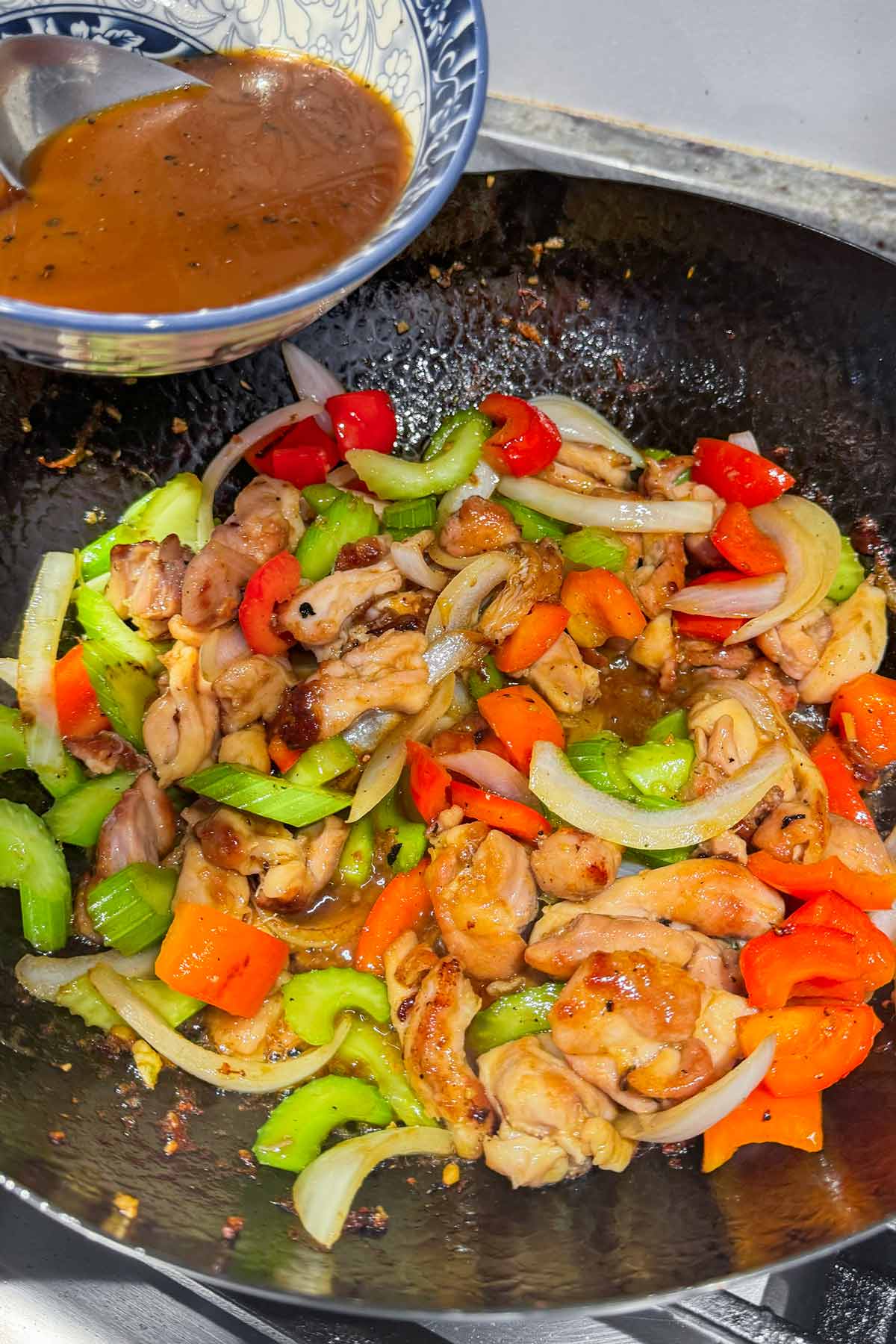 adding sauce to the black pepper chicken stir fry in the wok