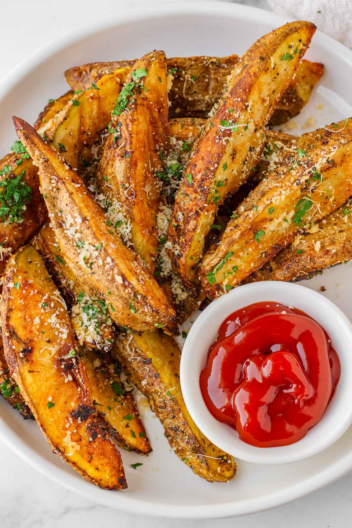 stacked potato wedges on plate with a side of ketchup