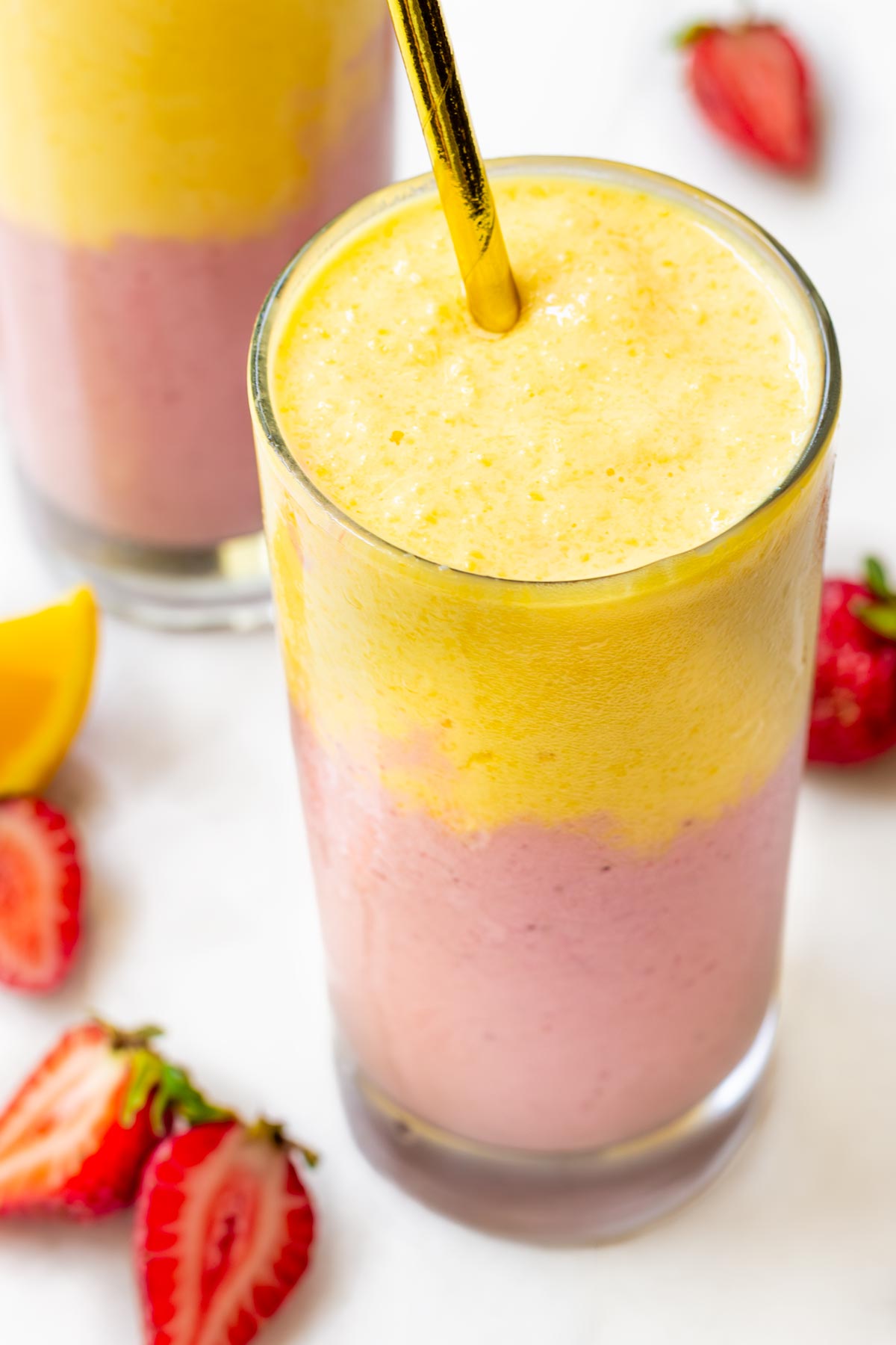 glass of strawberry mango smoothie with a paper straw