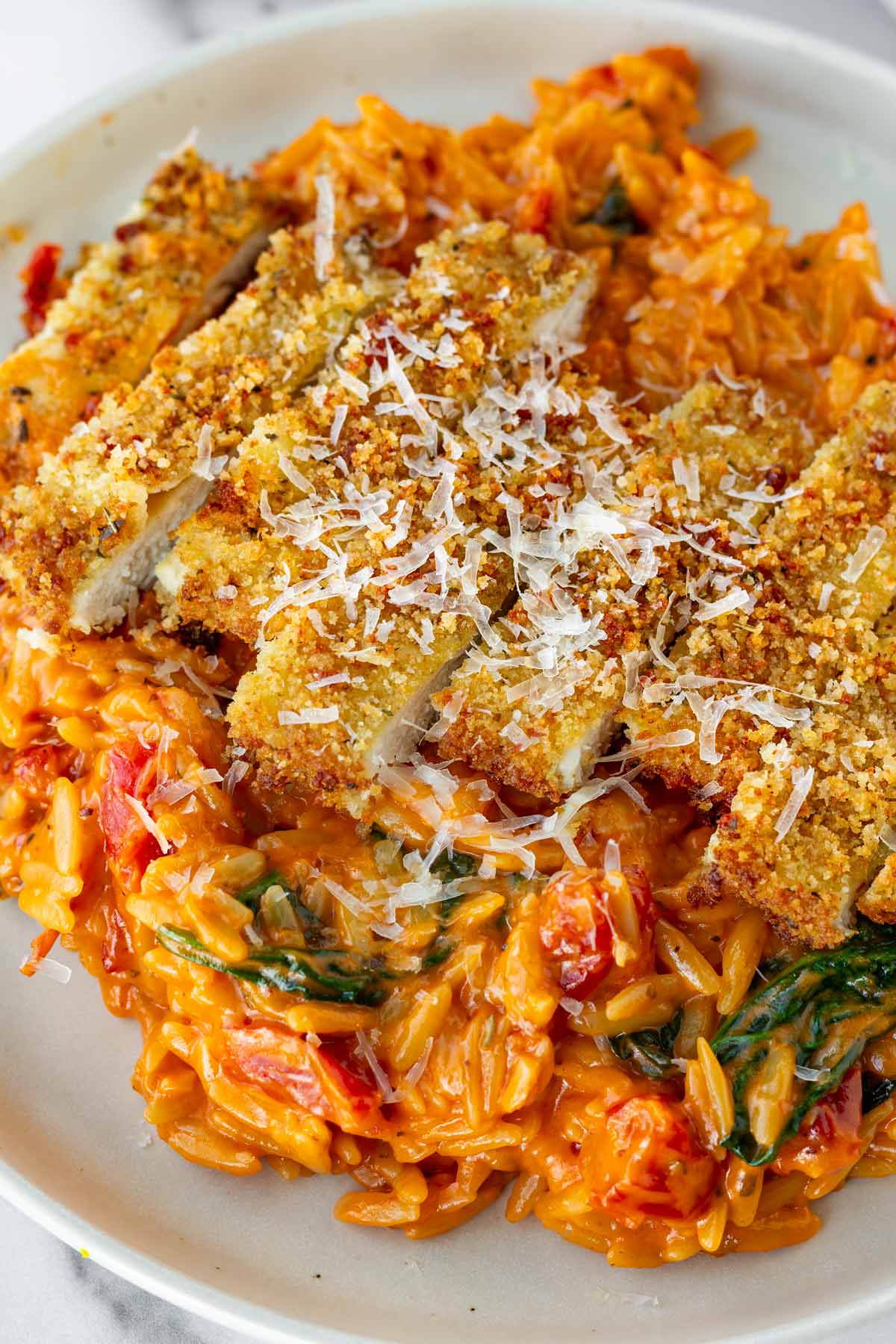 chicken cutlets served over tomato orzo