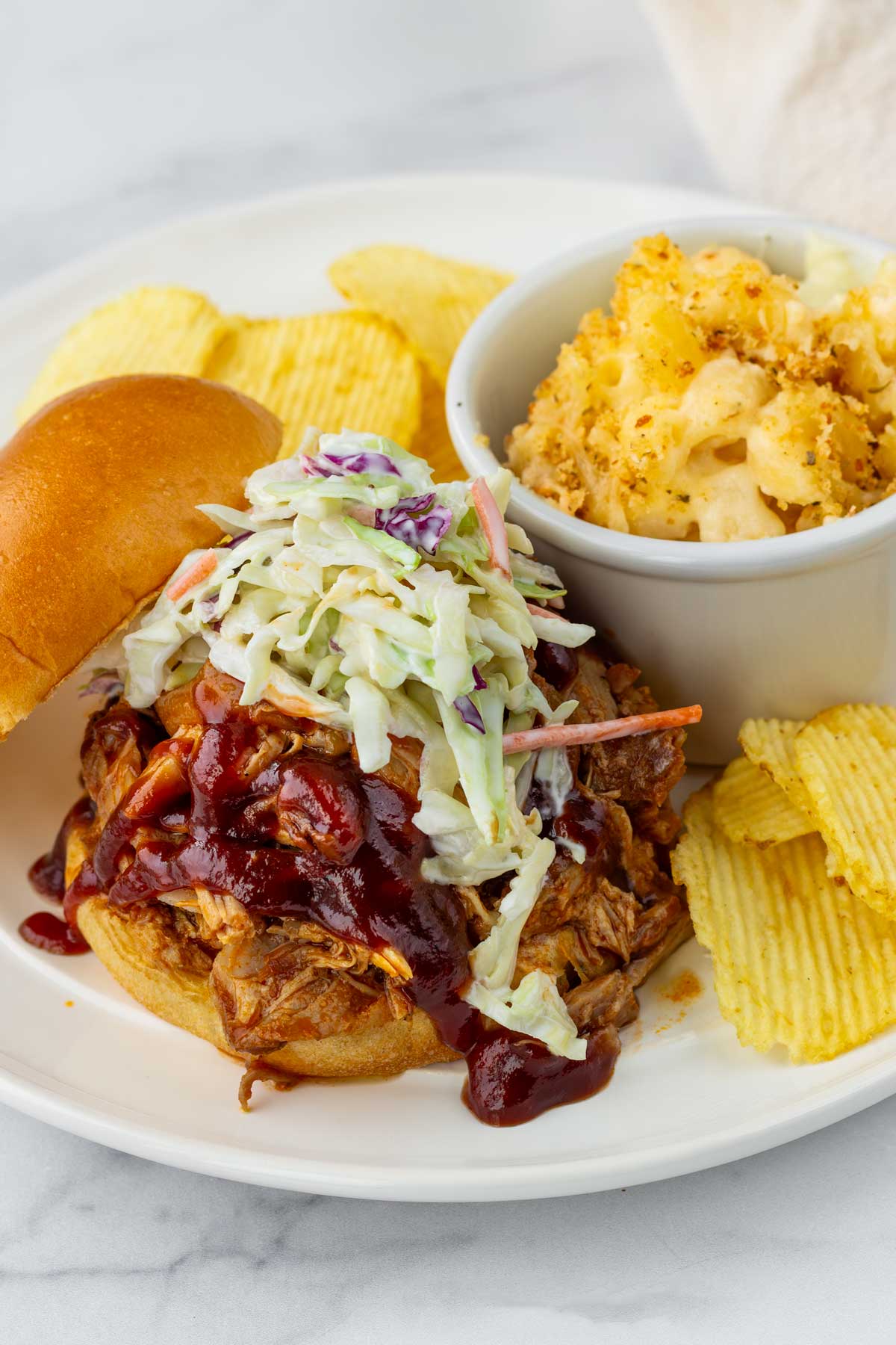 pulled pork sandwich with slaw, chips, and mac and cheese