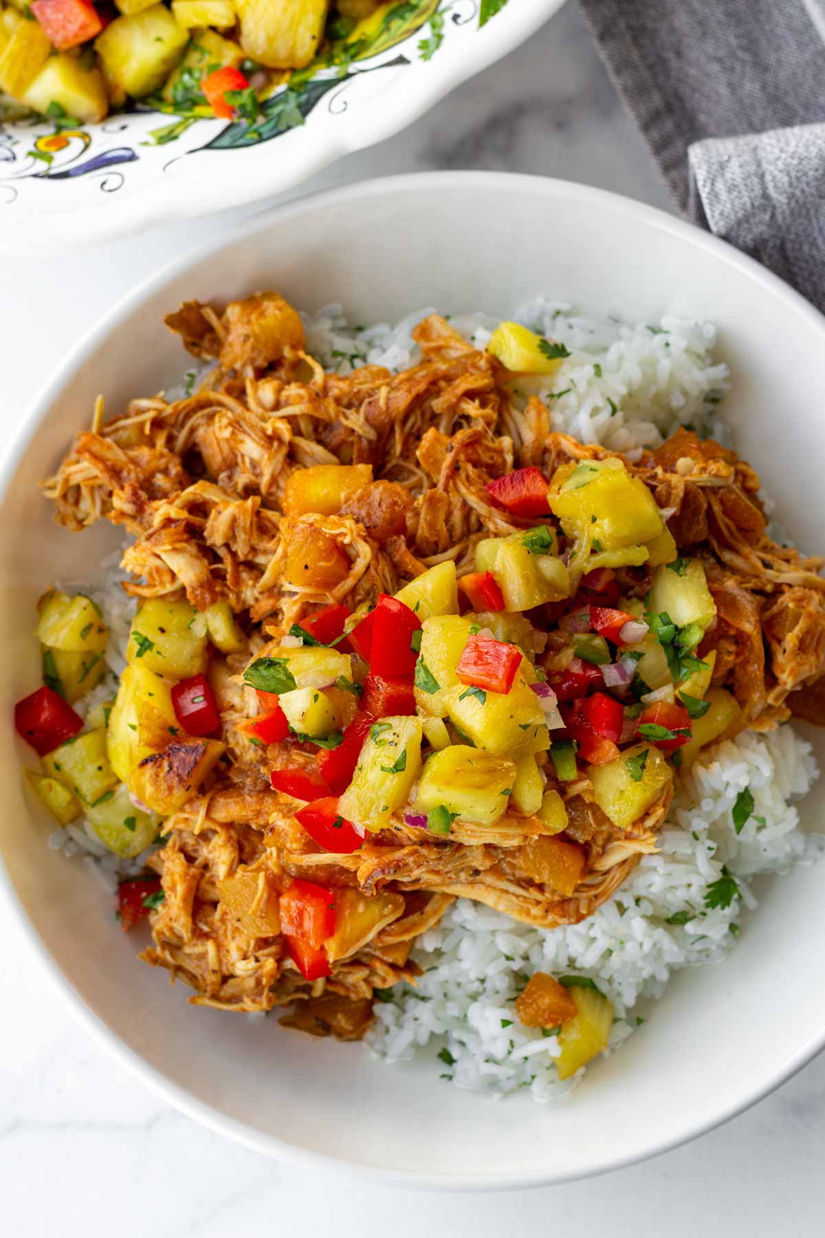 pineapple salsa over a bowl of pulled chicken with rice