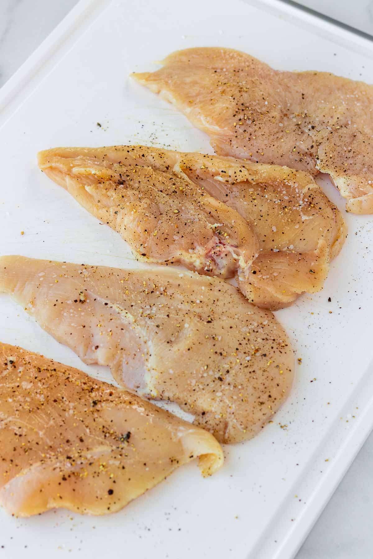 seasoned sliced chicken cutlets on cutting board