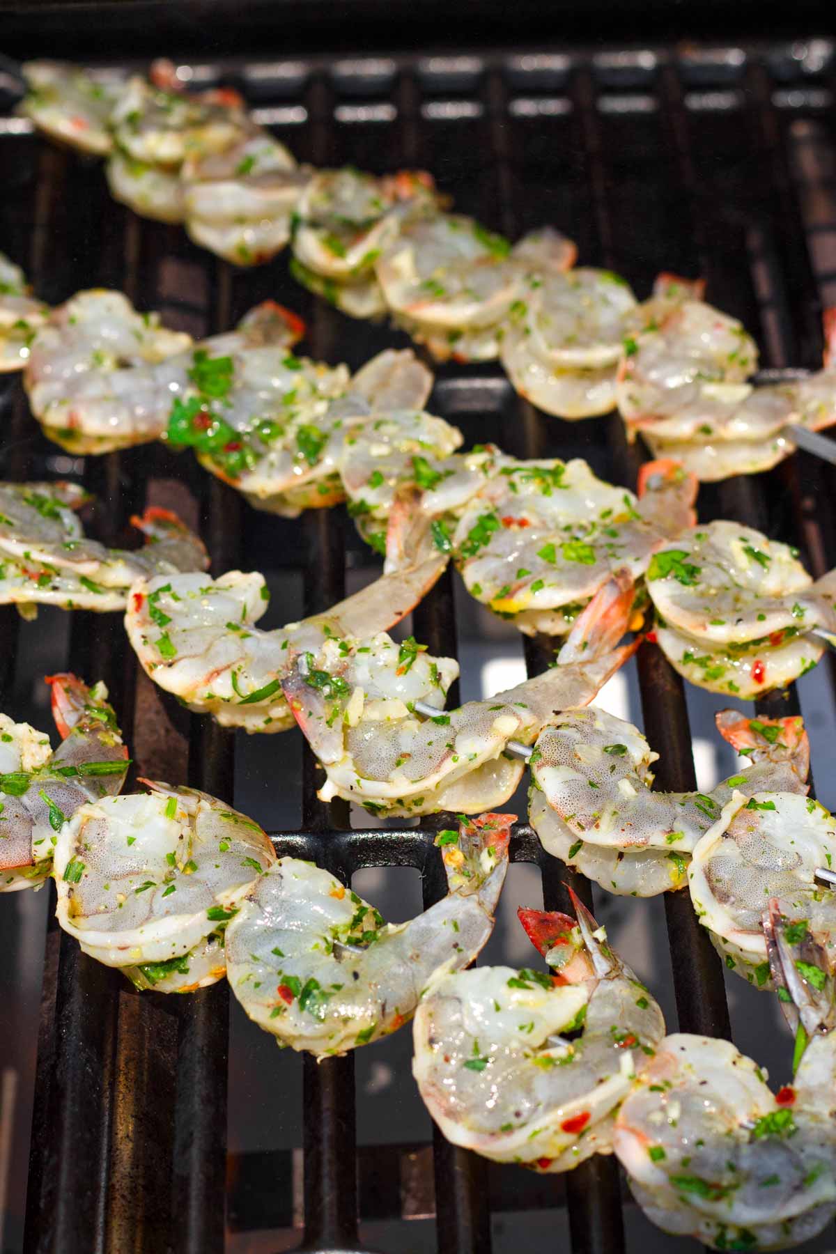 threaded marinated shrimp in metal skewers on the grill