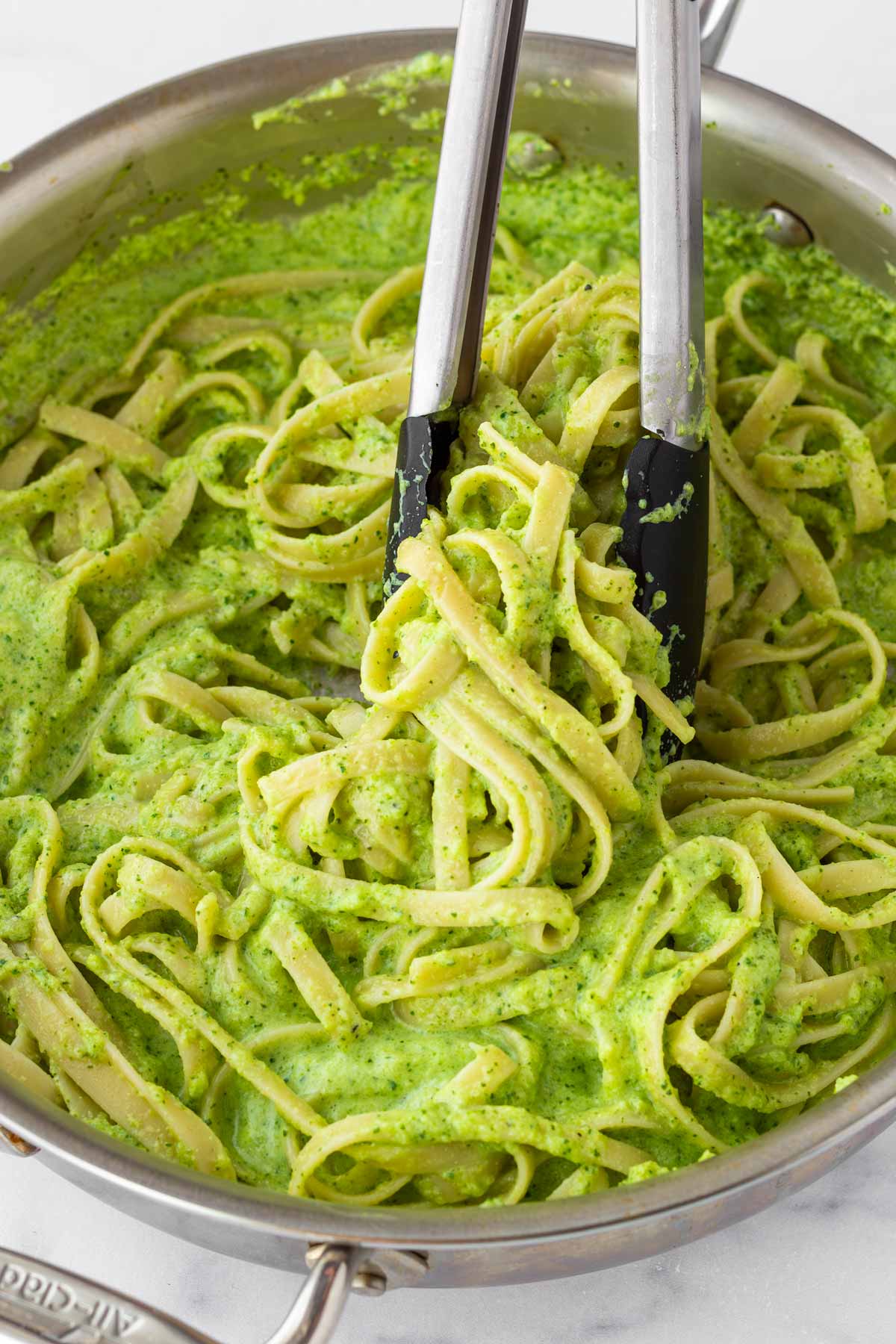 tossing pasta with sauce using tongs
