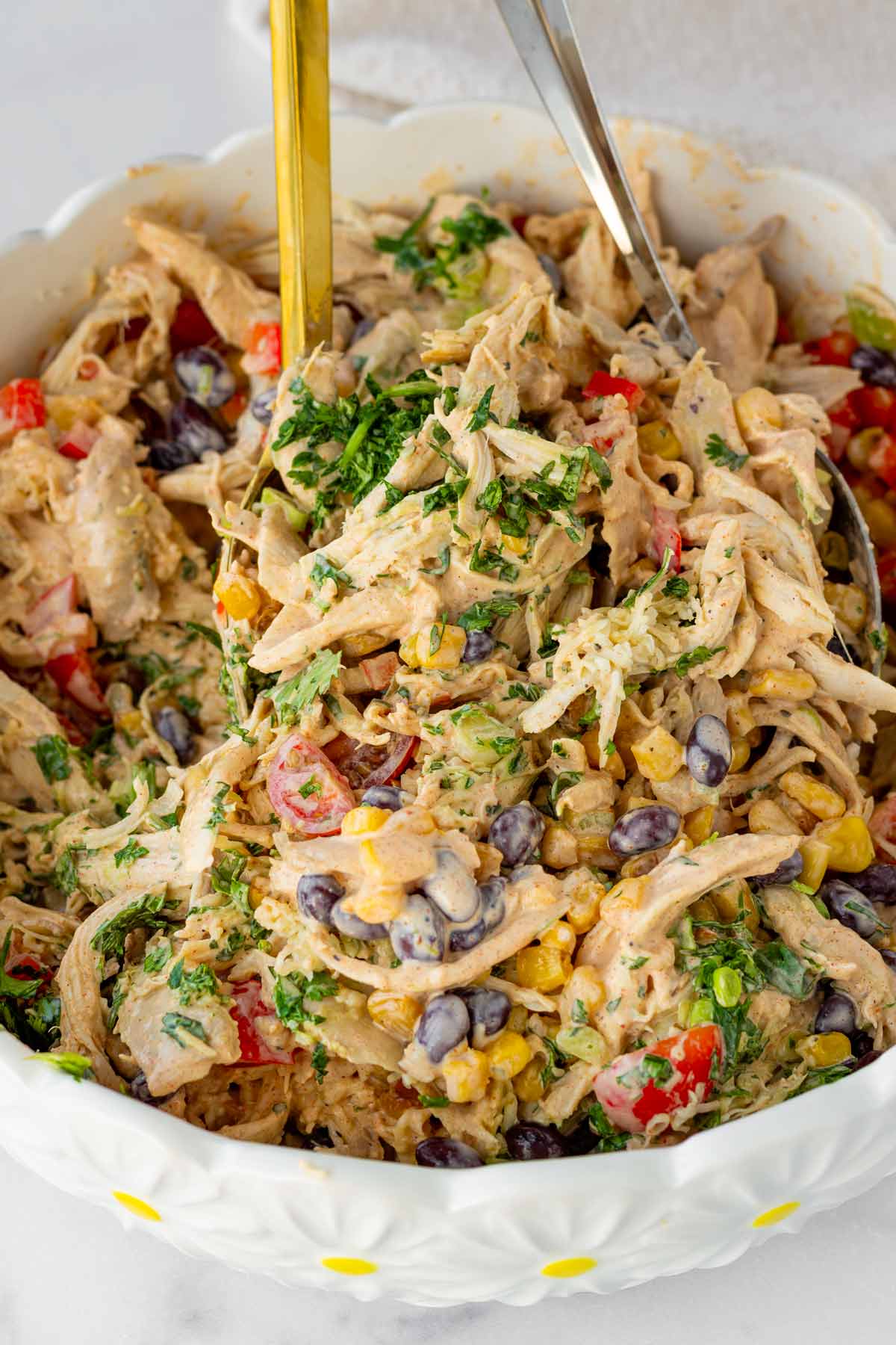 tossing southwest chicken salad with spoons to combine with dressing