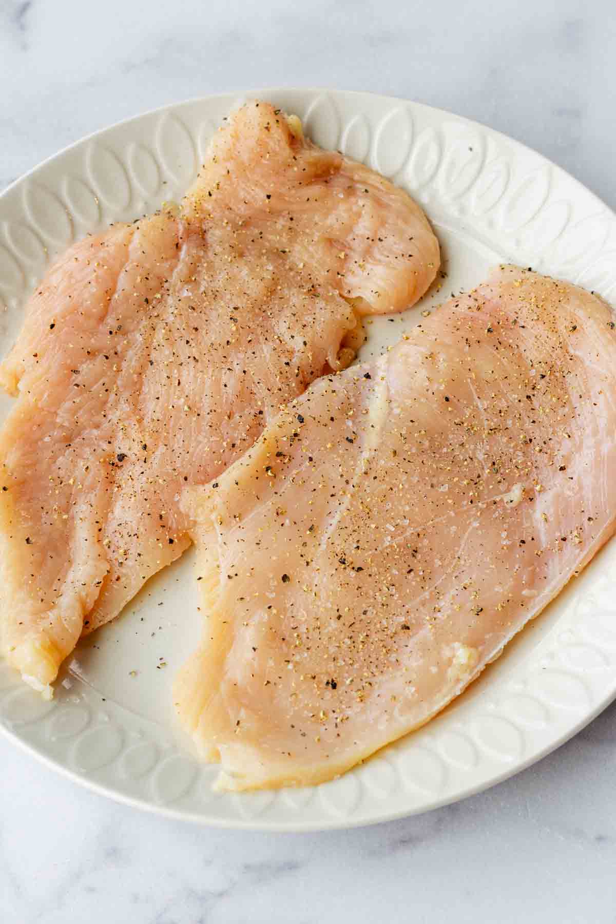 seasoning chicken cutlets with salt and pepper