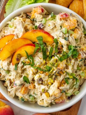 bowl with shredded peach chicken salad and a fresh garnish