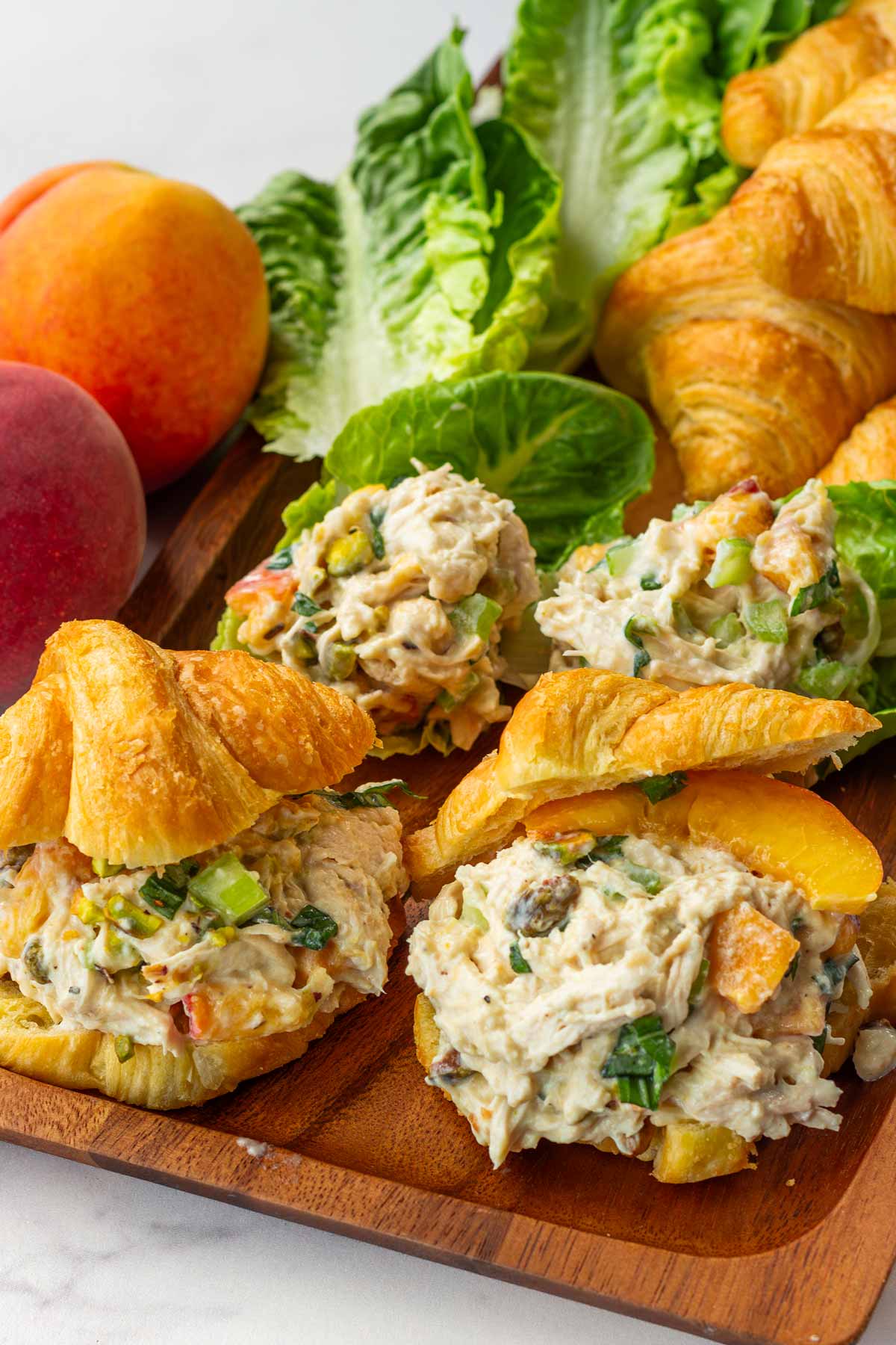 mini chicken salad with peach and basil served on croissant on a board