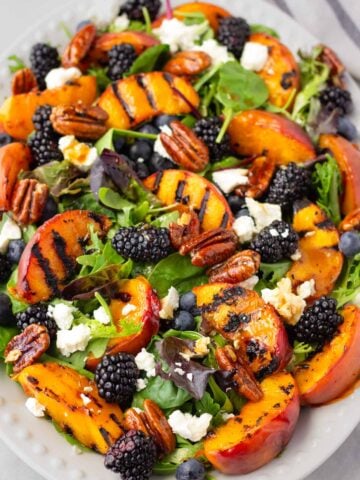 grilled peach salad with blackberries, blueberries, feta, and candied pecans