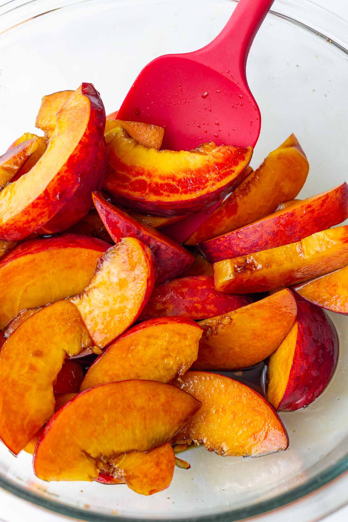 tossing sliced peaches with balsamic vinegar and brown sugar