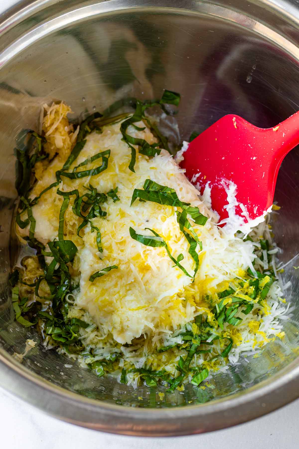 mixing ricotta with basil, parmesan, basil, lemon zest in a metal bowl