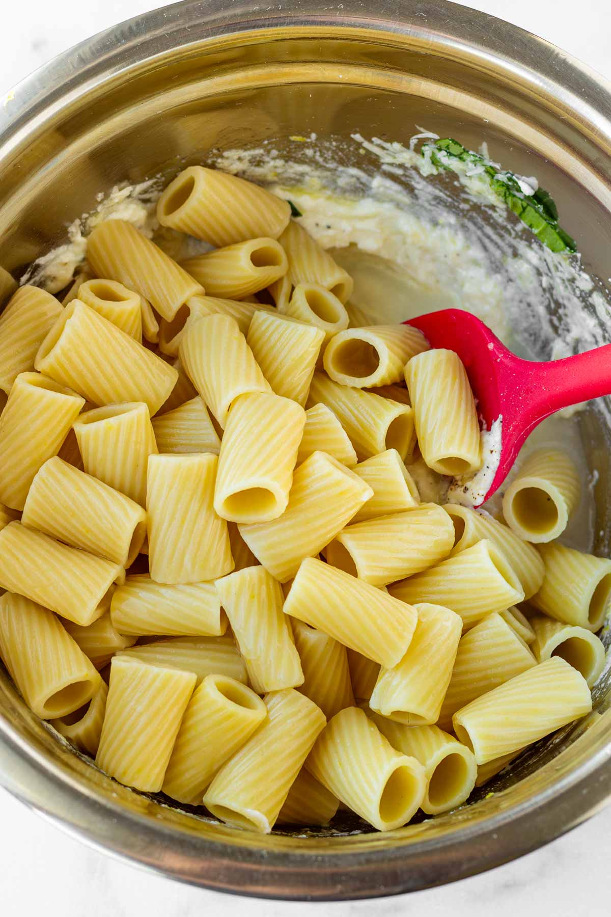 adding cooked hot pasta into the sauce along with pasta water