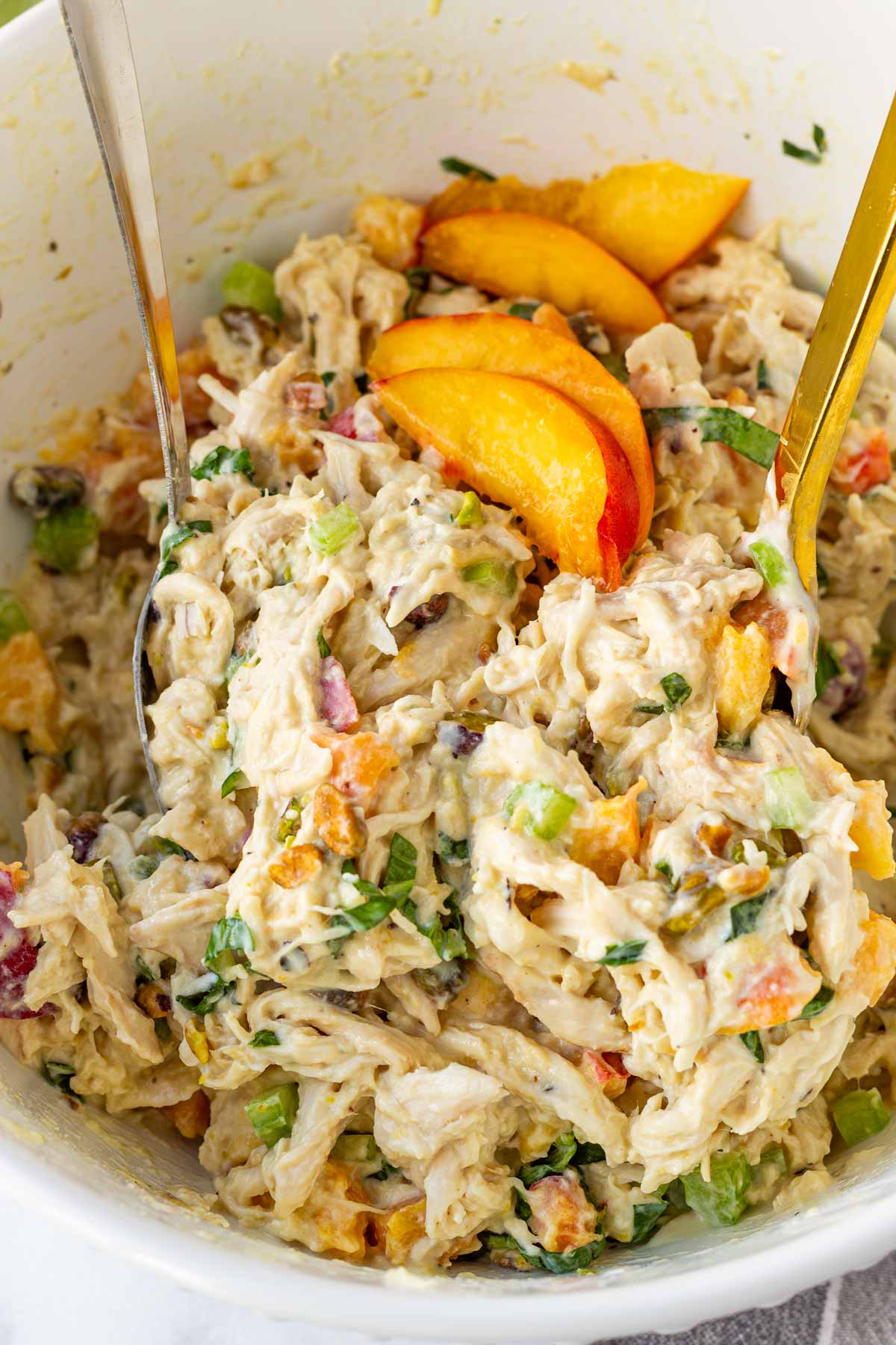 mixing the peach shredded chicken salad with spoons