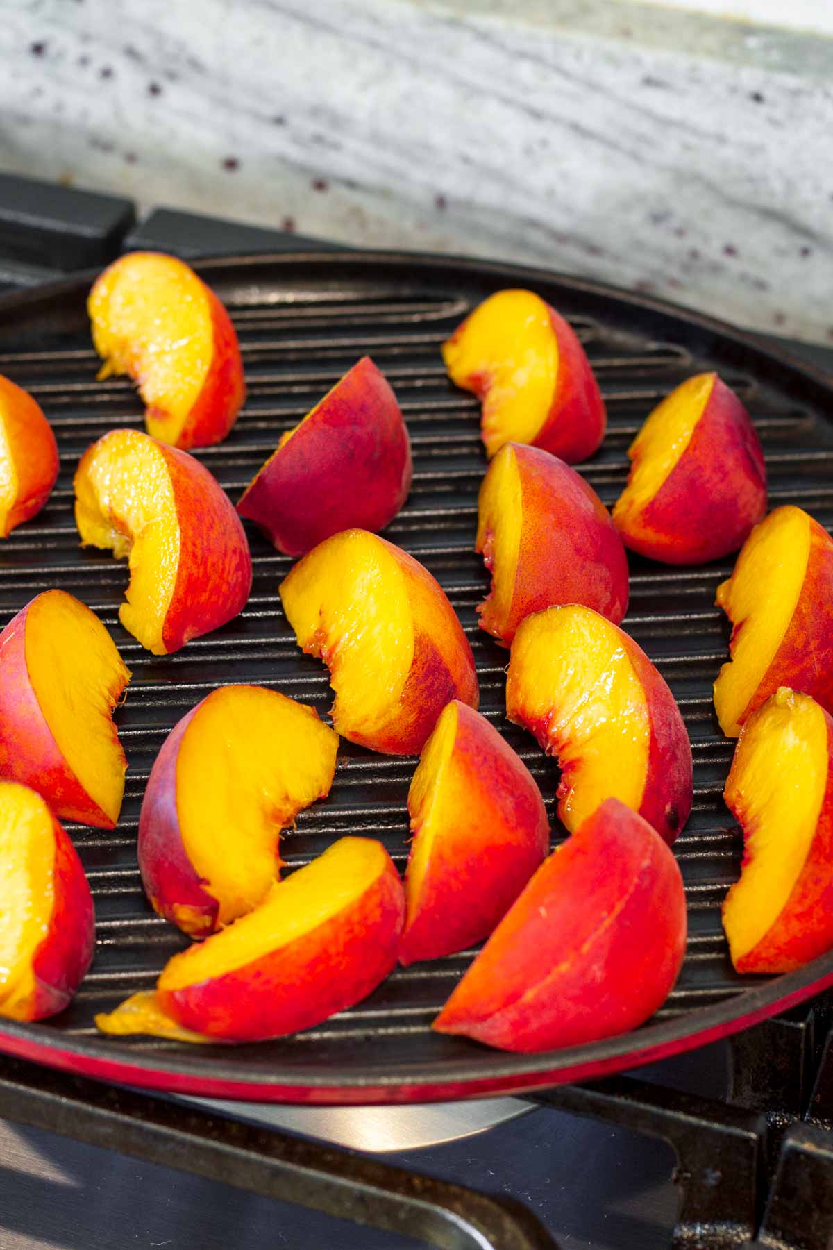 grilling peach wedges in a round grill pan