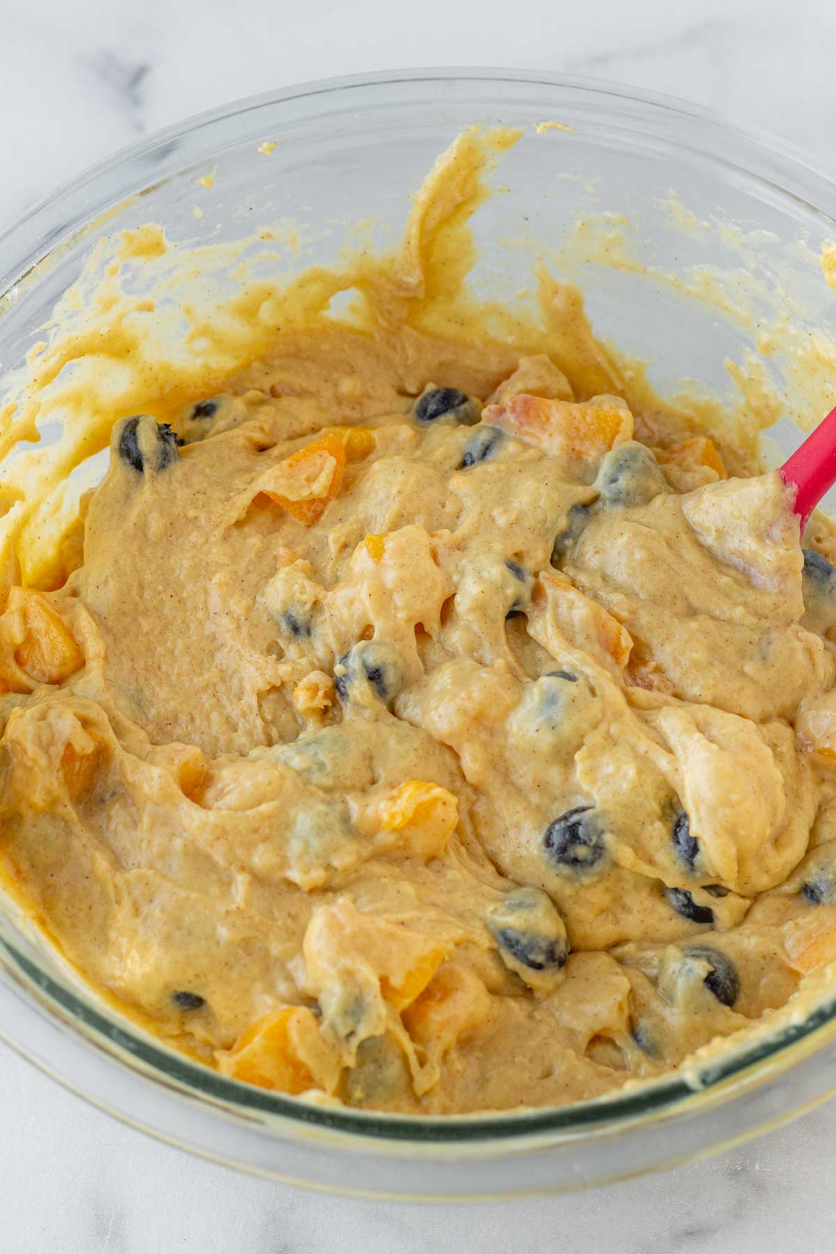 mixing peaches and bluberries into batter