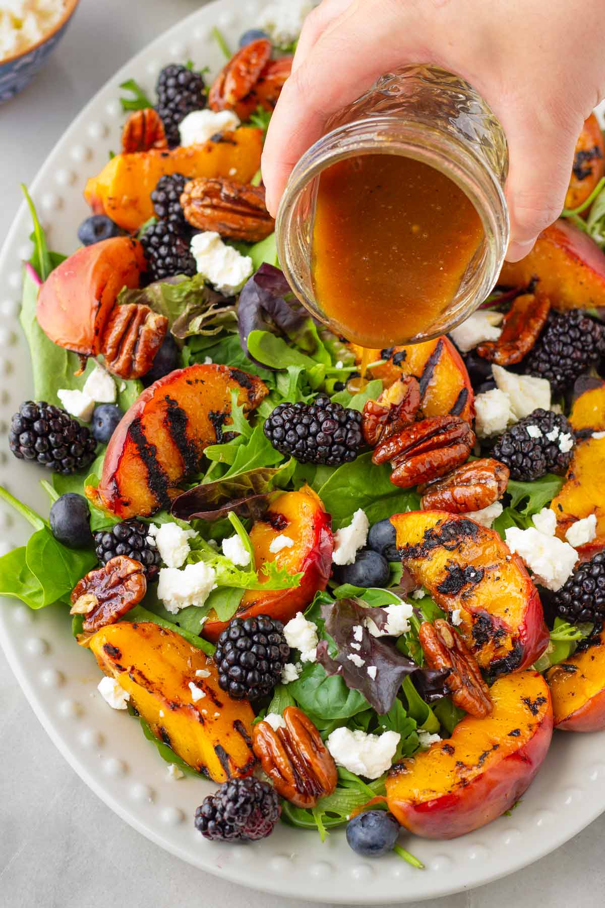 adding balsamic dressing to the peach salad