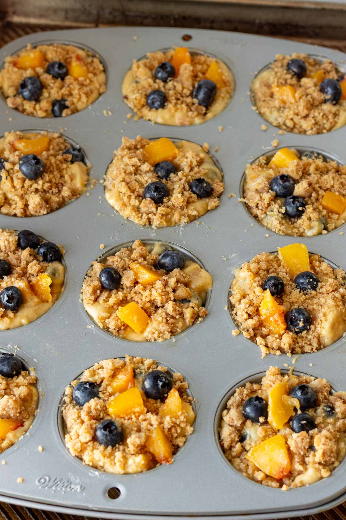 topping and fruit added on top of the batter in the muffin pan